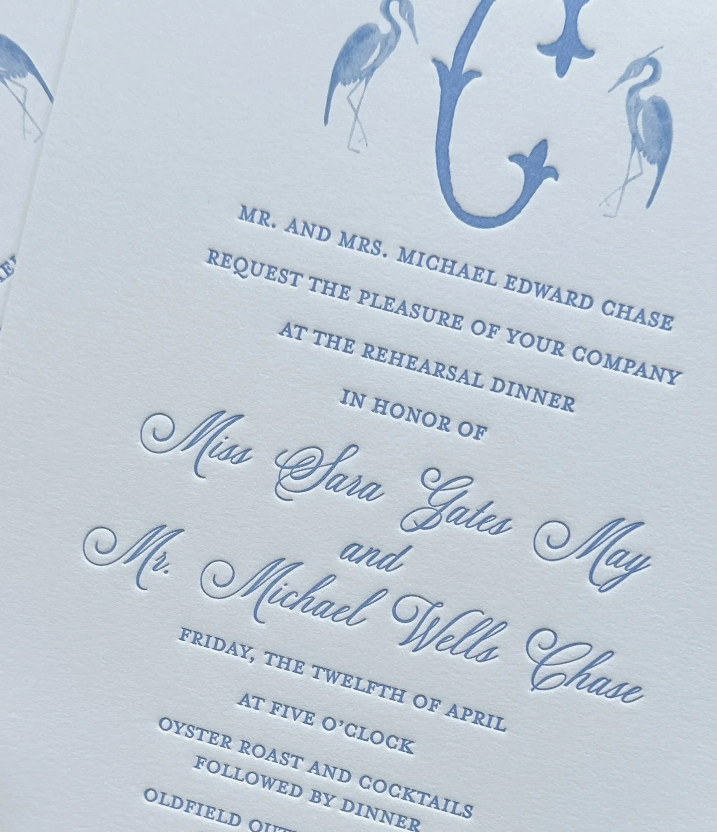 Elegant wedding invitation with blue and white color scheme, featuring waterfowl illustrations and formal text.