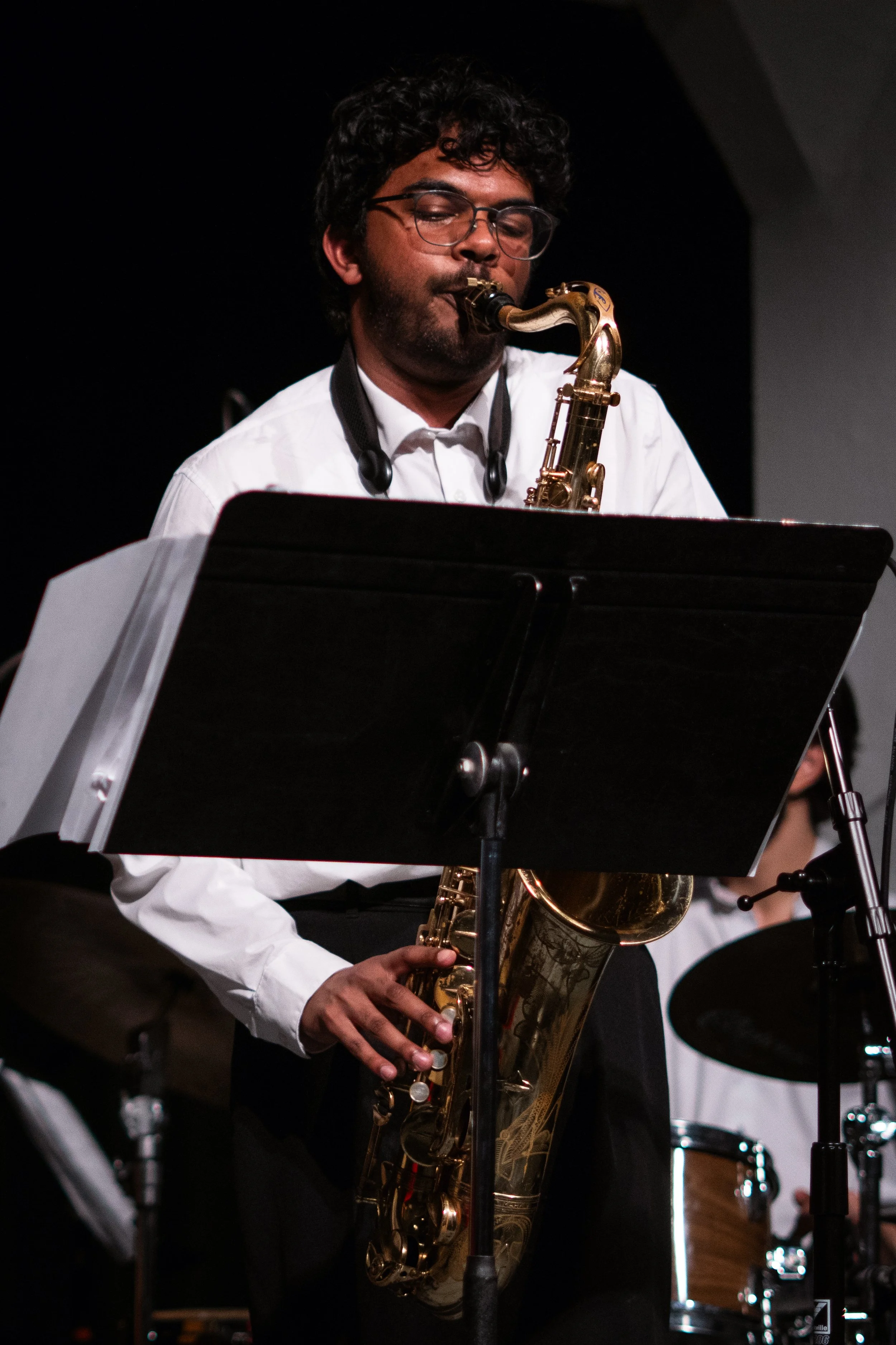 Musician playing a saxophone behind a music stand.