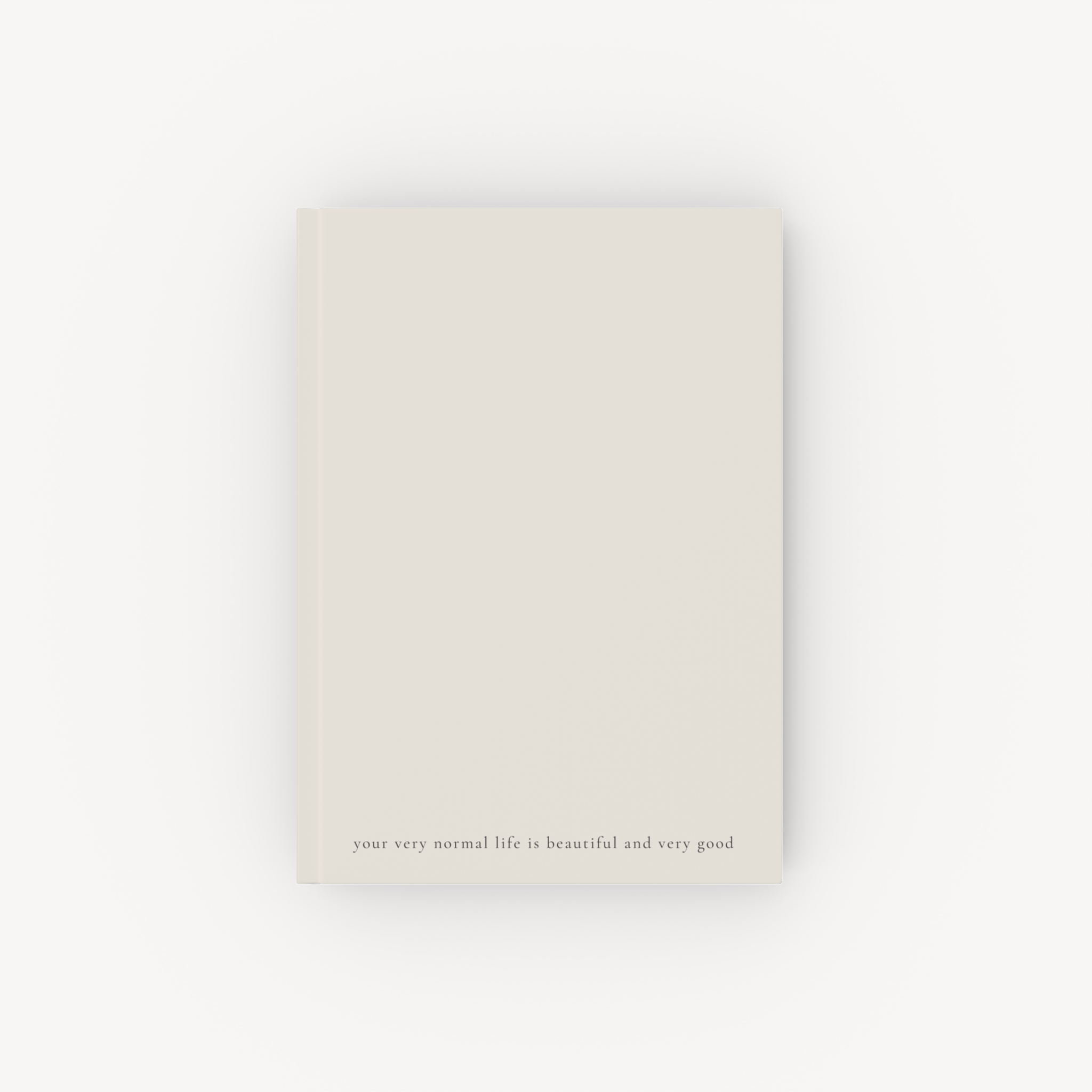 Minimal beige hardcover notebook with small text near the bottom on a pale background.