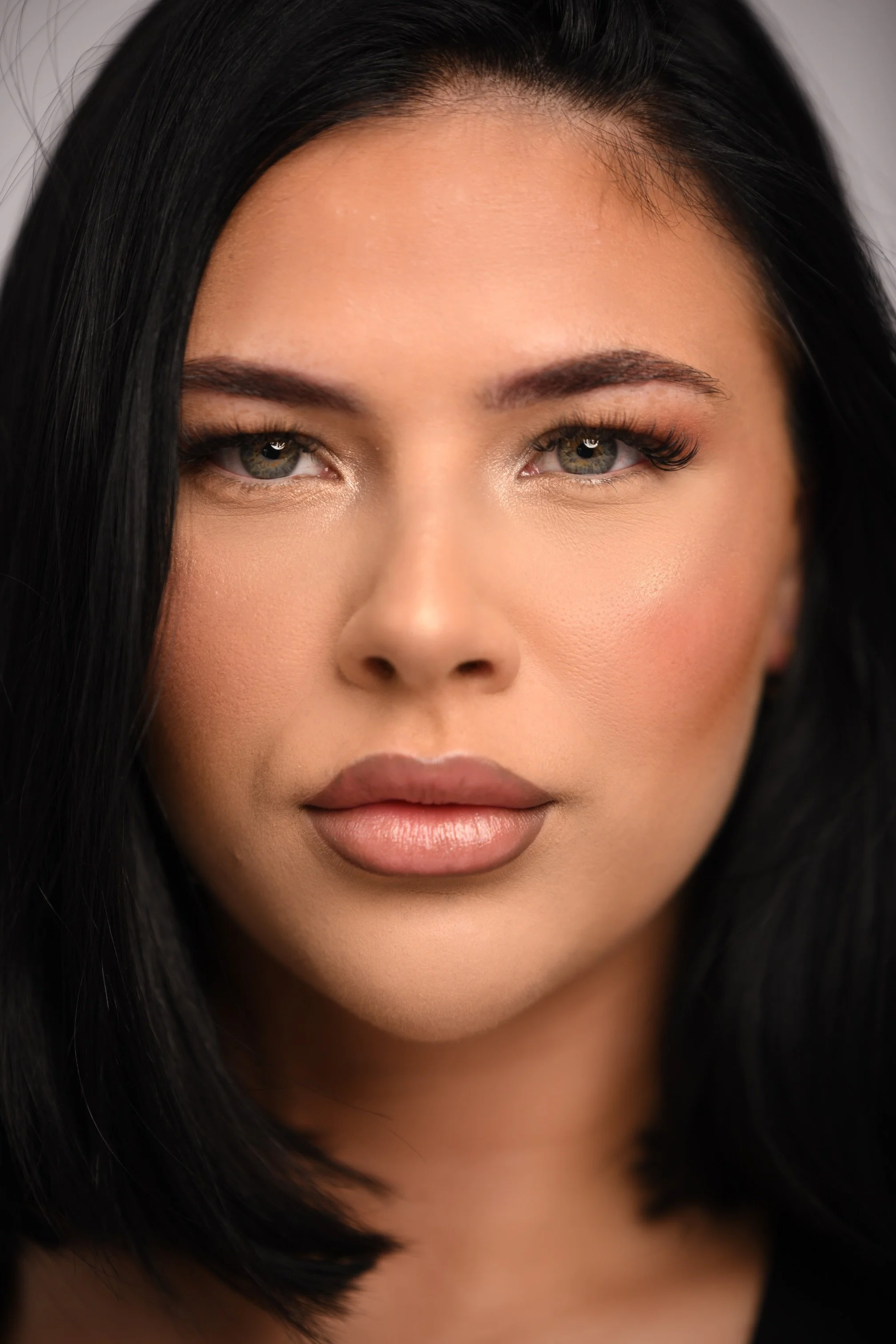 A modern wooden house overlooking a body of water with mountains in the background, during sunset or sunrise.