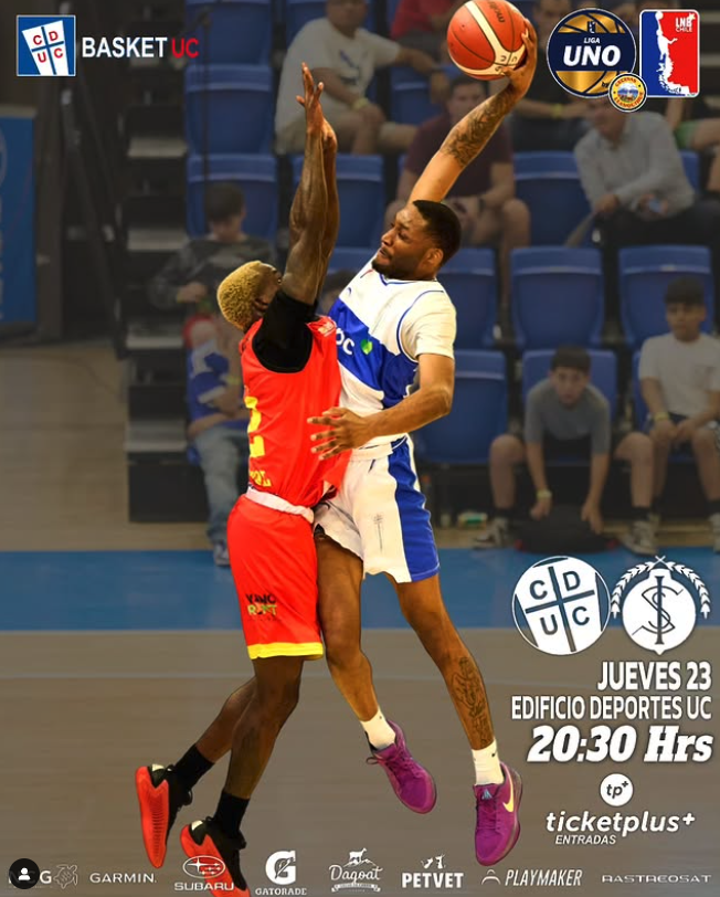 Dos jugadores de baloncesto en acción en una cancha cubierta, uno en uniforme negro y rojo y otro en uniforme blanco y azul, disputan el balón durante un partido de la Liga UNO, con espectadores en las gradas y anuncios en el fondo.