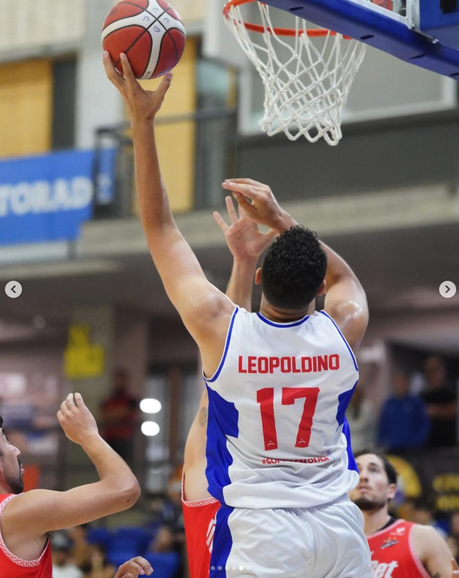 Jugador de baloncesto con camiseta que dice Leopoldino y número 17, saltando para encestar o bloquear en un partido en interiores.
