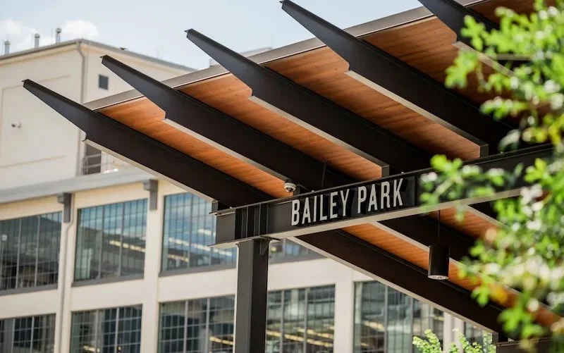 Street sign reading Bailey Park with modern architectural building in the background