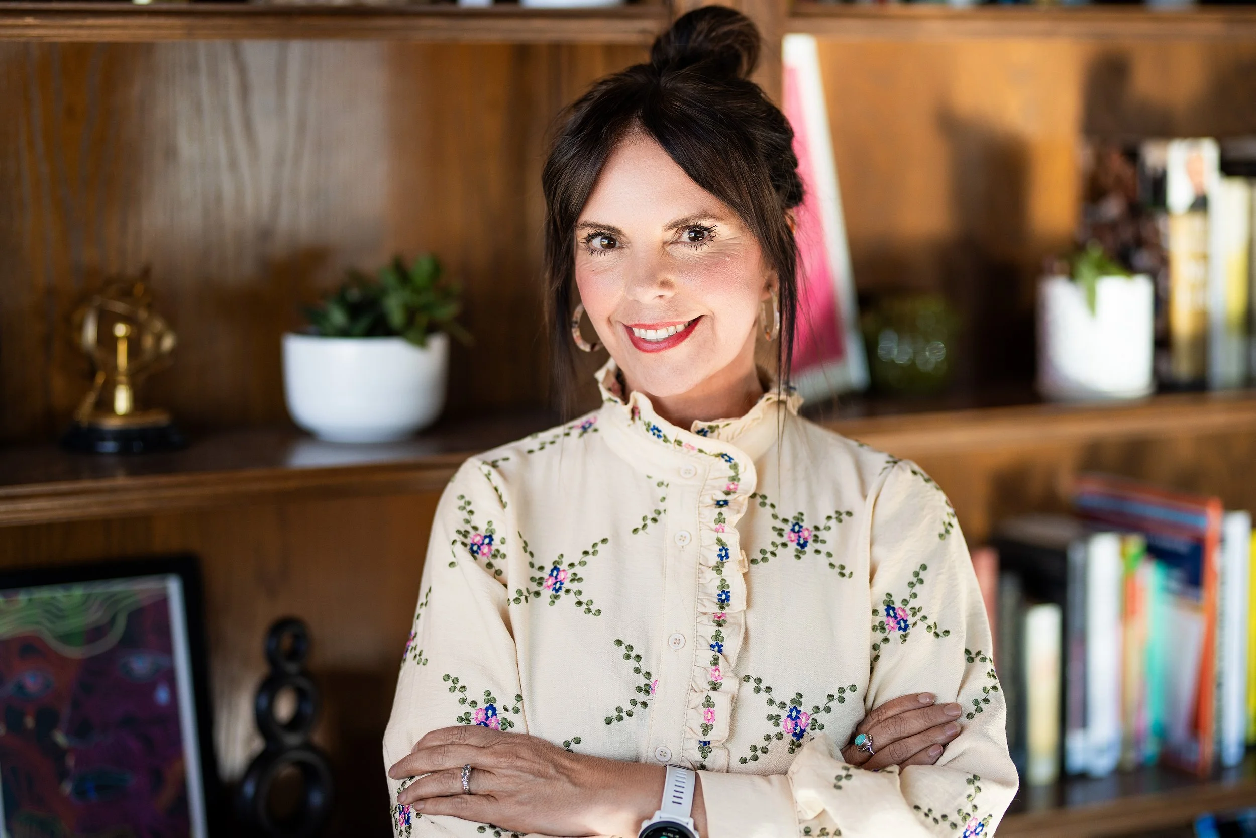 A woman counselor/therapist with long brown hair smiling at the camera, wearing a light blue blouse and hoop earrings.