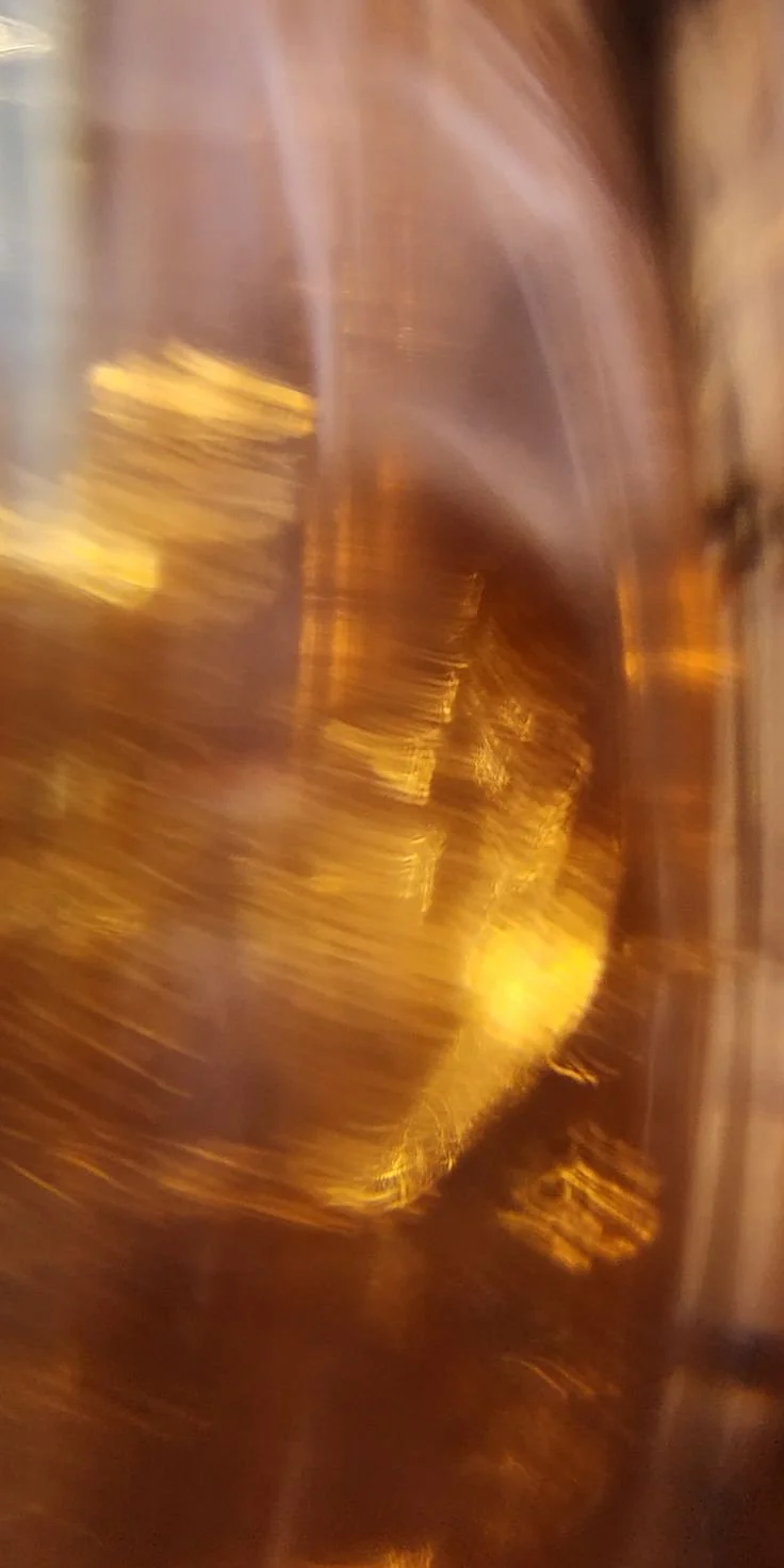 Abstract, blurry, golden-brown swirls with streaks of yellow light and reflections.