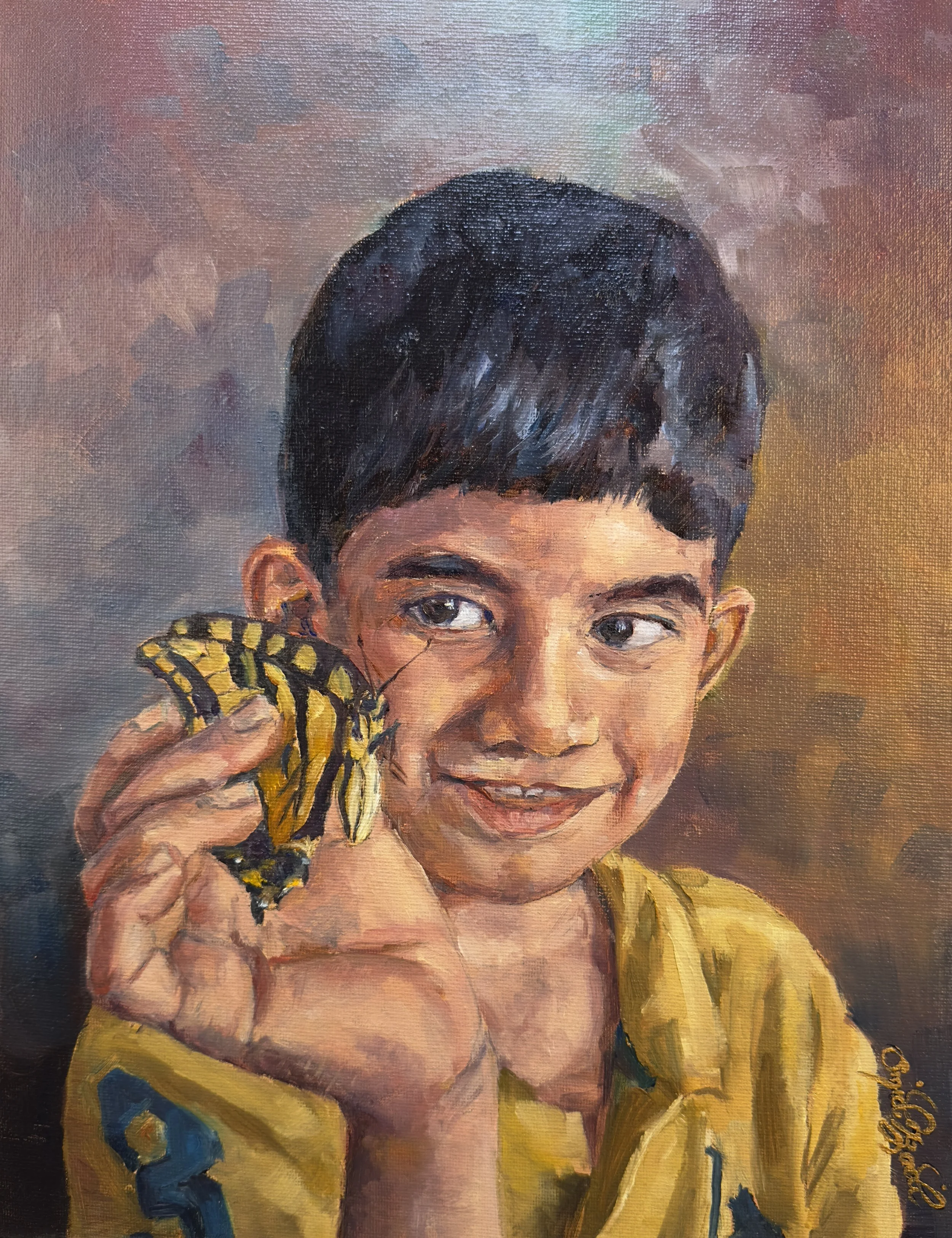A young boy with short dark hair smiling and holding a yellow and black butterfly near his face.