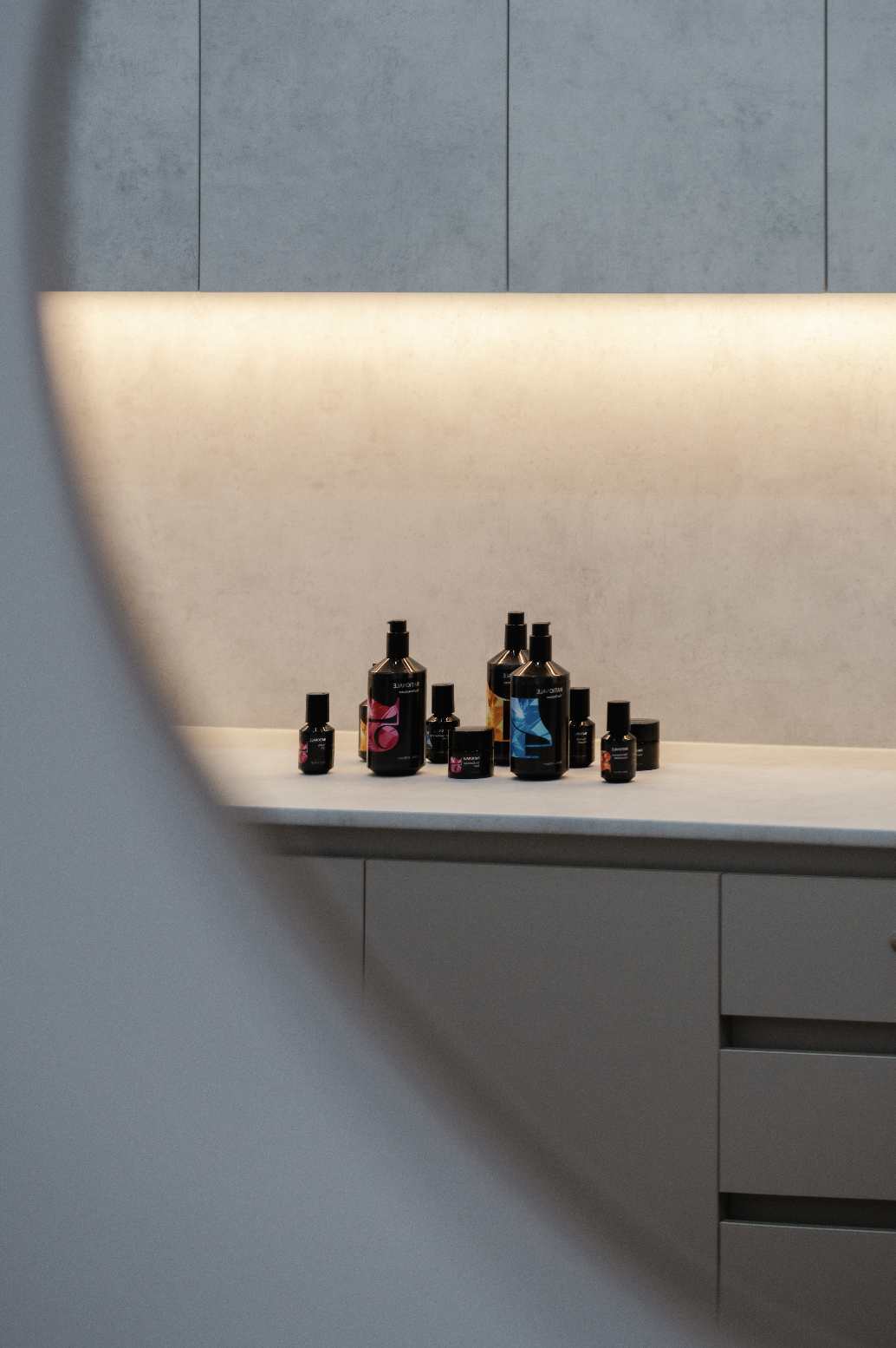 Assorted black bottles with colored labels on a countertop in a modern kitchen setting.