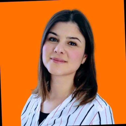 Jeune femme avec des cheveux bruns, portant une chemise à rayures, contre un fond orange.