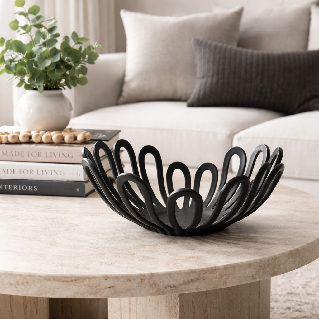A sculptural black metal bowl displayed on a coffee table.
