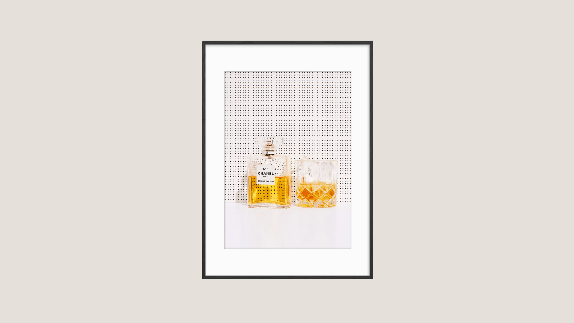 An art print featuring a bottle of perfume and a tumbler with ice, with a black frame.