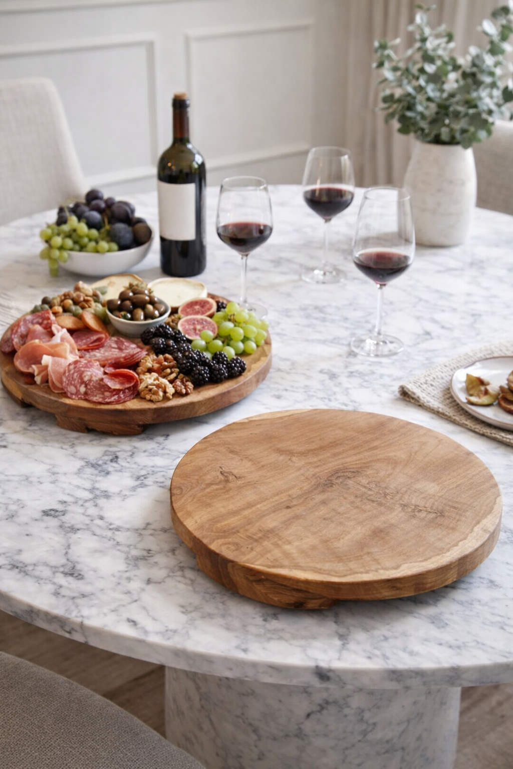 A natural wood board styled on a dining table with charcuterie.