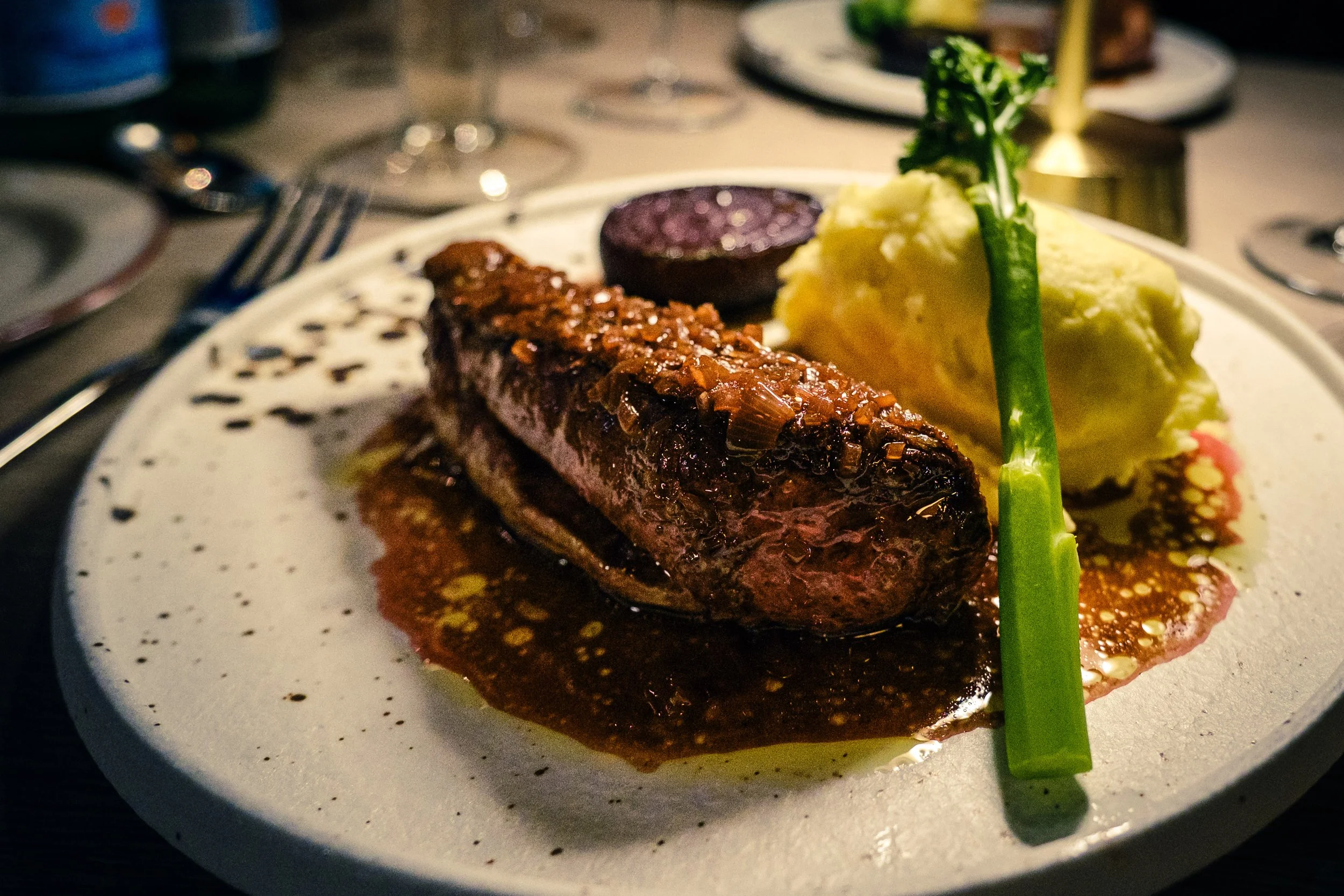 Andebryst med potetmos, grønne urter og saus på en tallerken