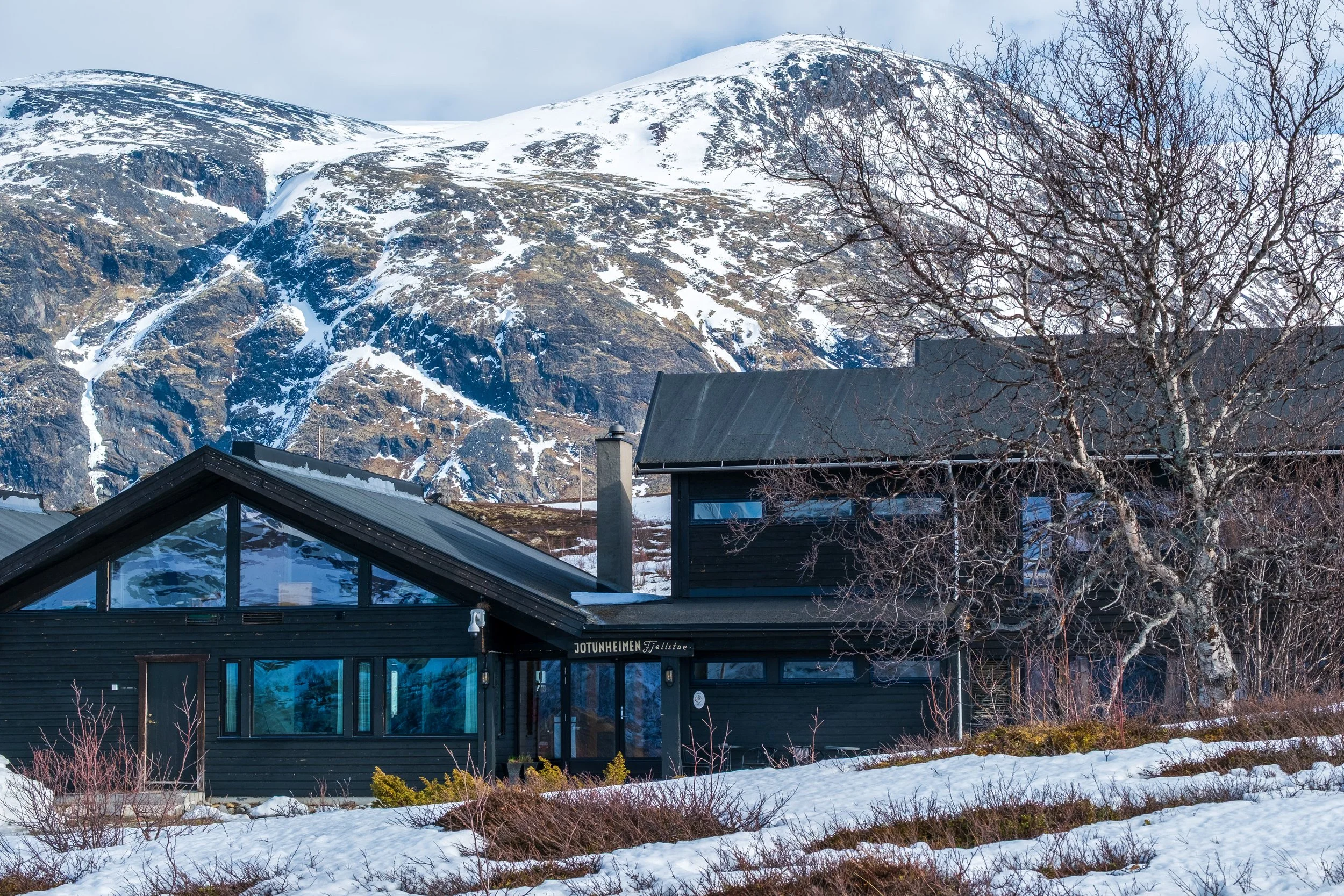 Jotunheimen Fjellstue i landskap med fjell i bakgrunnen.