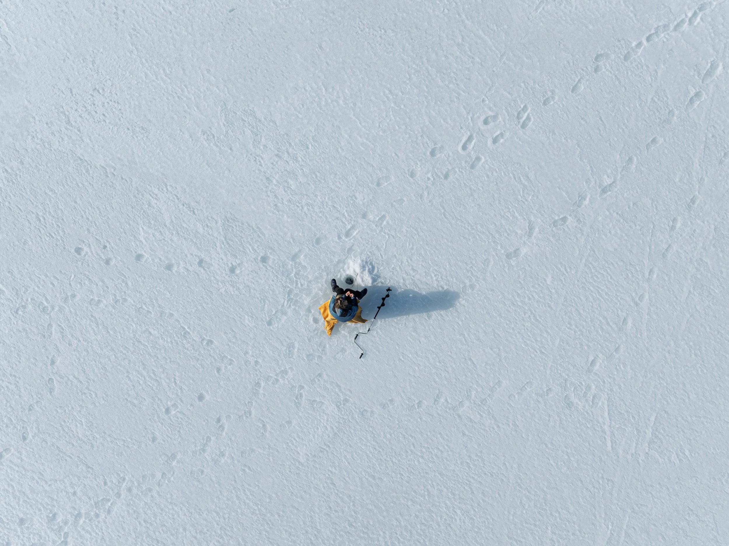 En person isfisker på vannet utenfor Jotunheimen Fjellstue sett ovenfra.