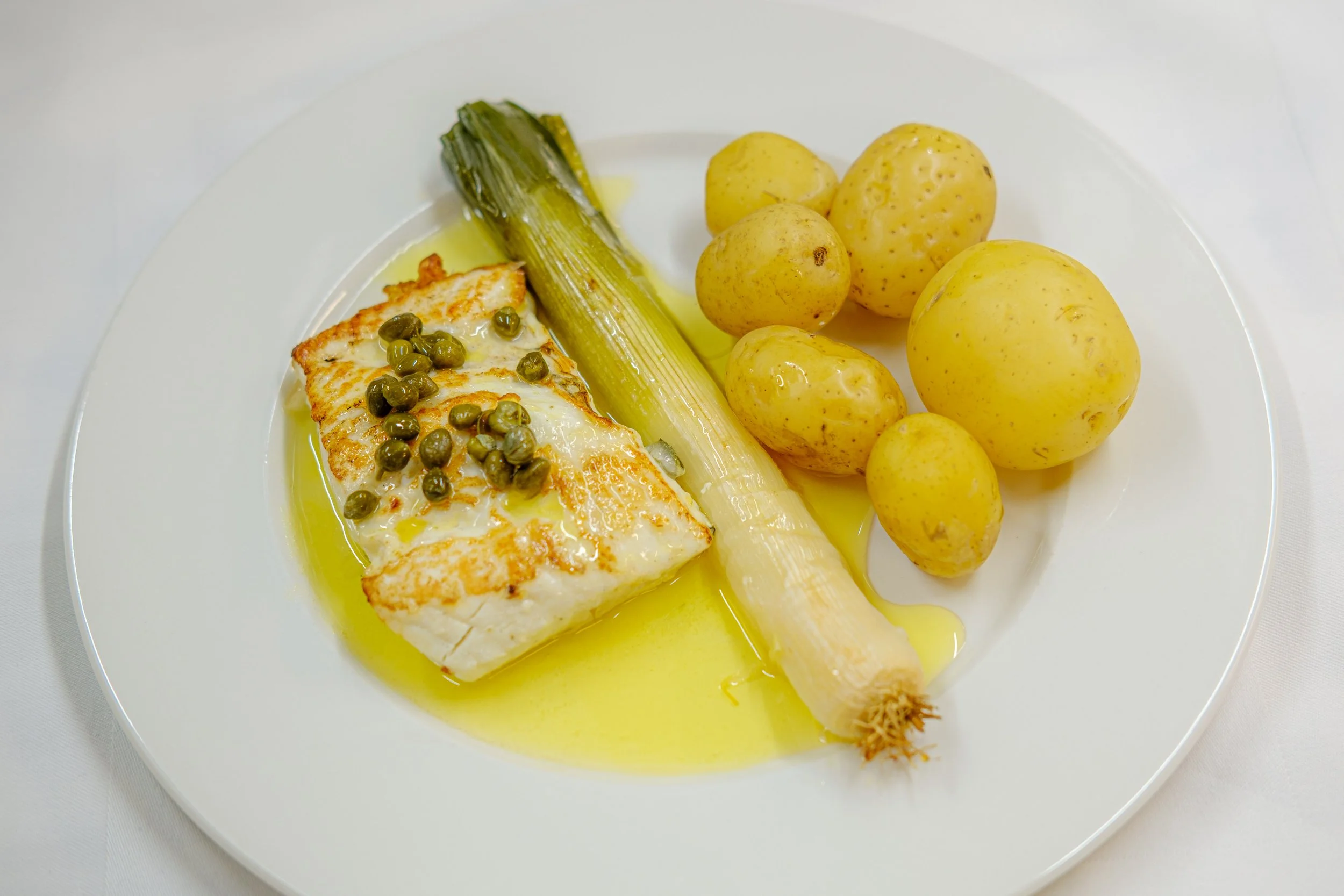 Tallerken med stekt fisk med poteter og grønnsaker. 