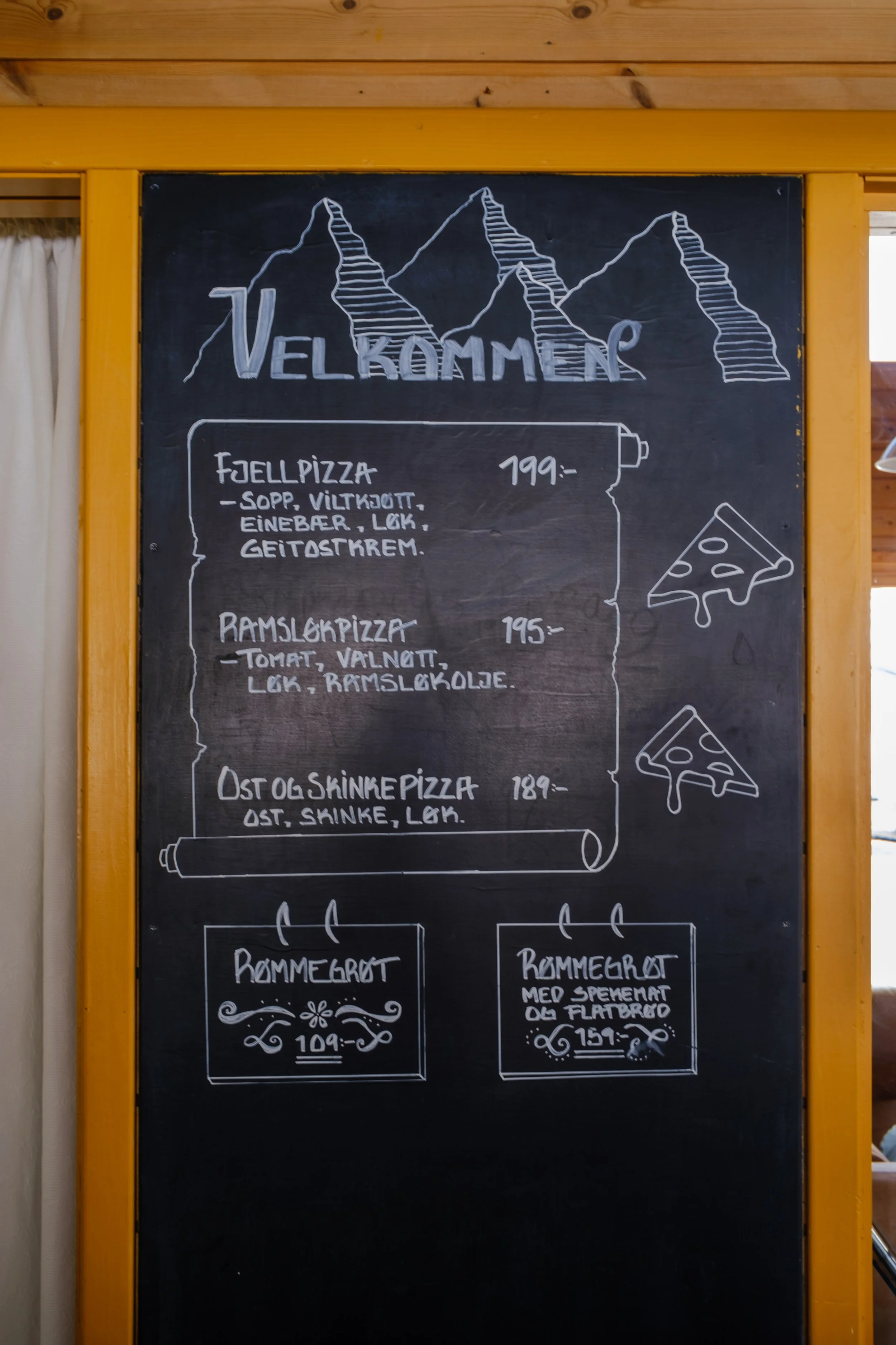 Tavle med meny, overskrift 'Velkommen', tegning av fjell, bilder av pizza, og to priser for ulike typer brød.