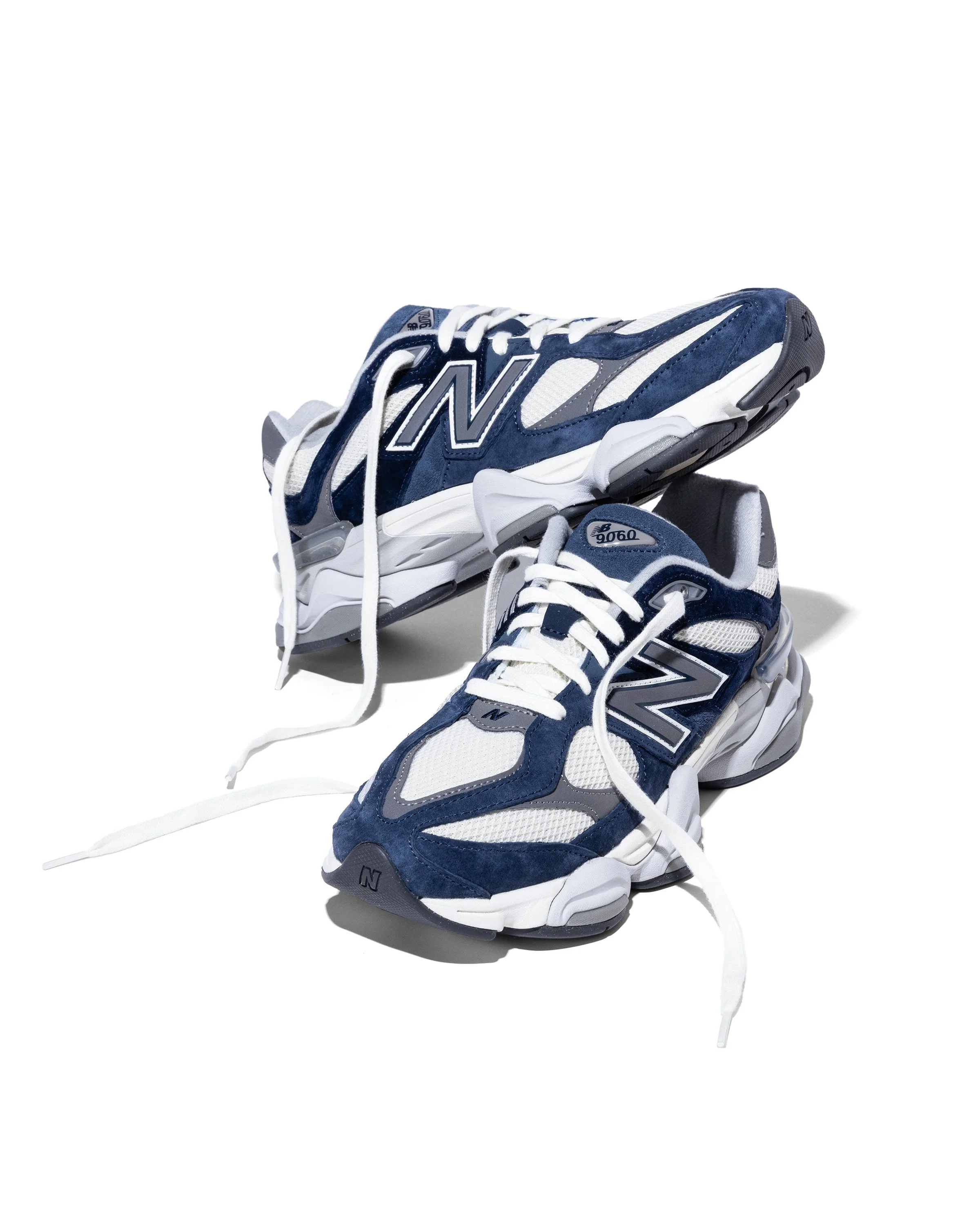 Paire de baskets New Balance, blanches, bleues et gris, sur fond blanc.