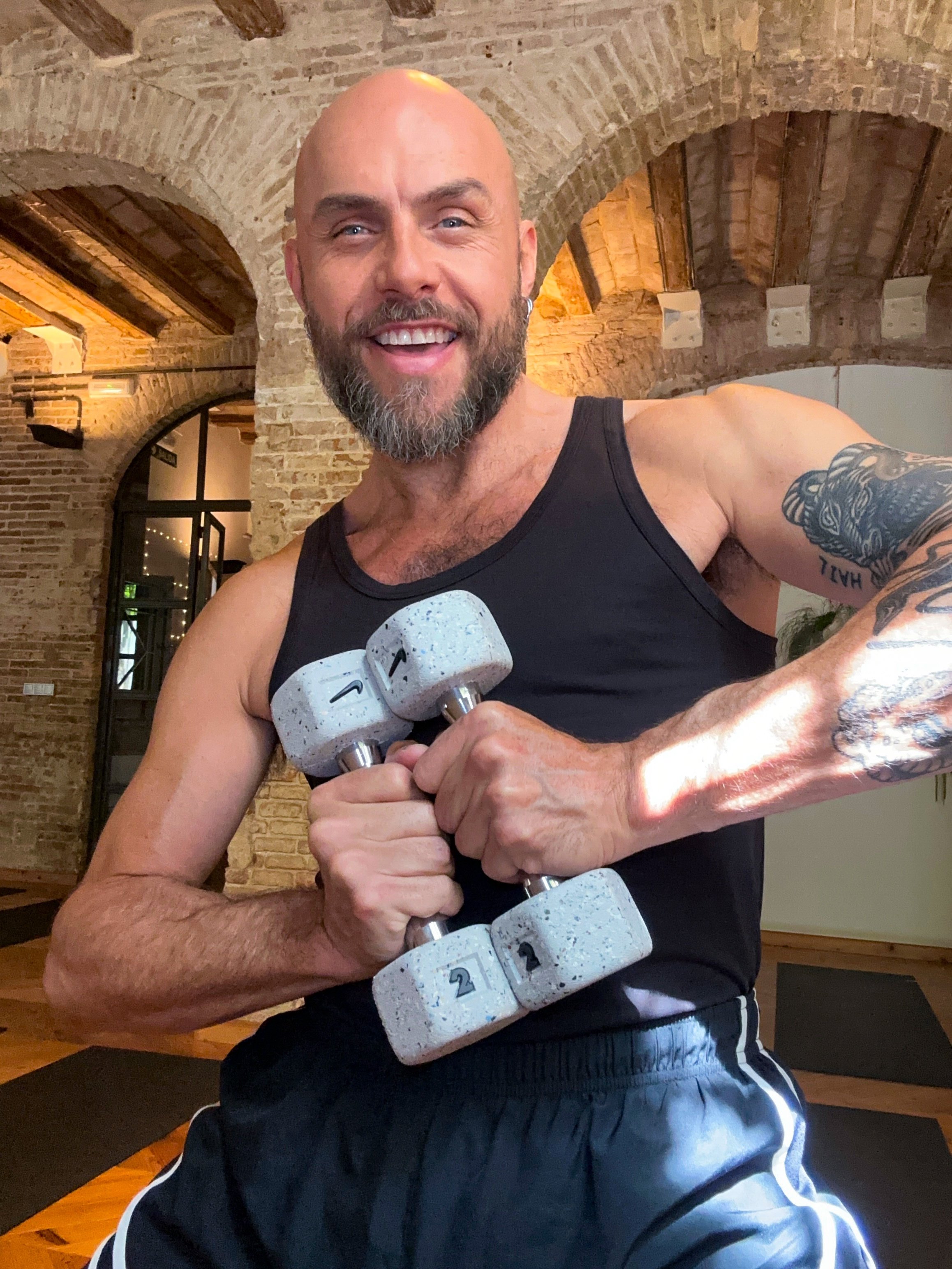 Man holding dumbbells indoors with exposed brick and wooden beams