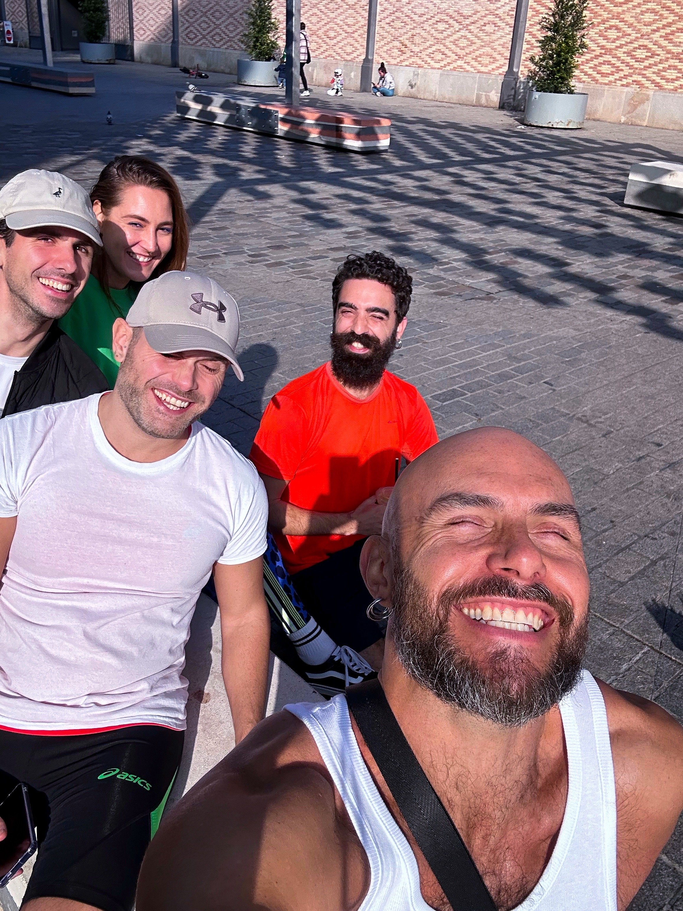 Group of five people smiling outdoors in sunny weather
