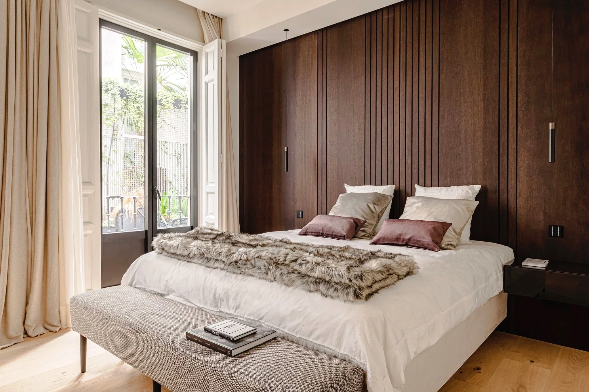 Dormitorio de Barquillo 47 con panelado de madera natural y vistas a uno de sus jardines privados