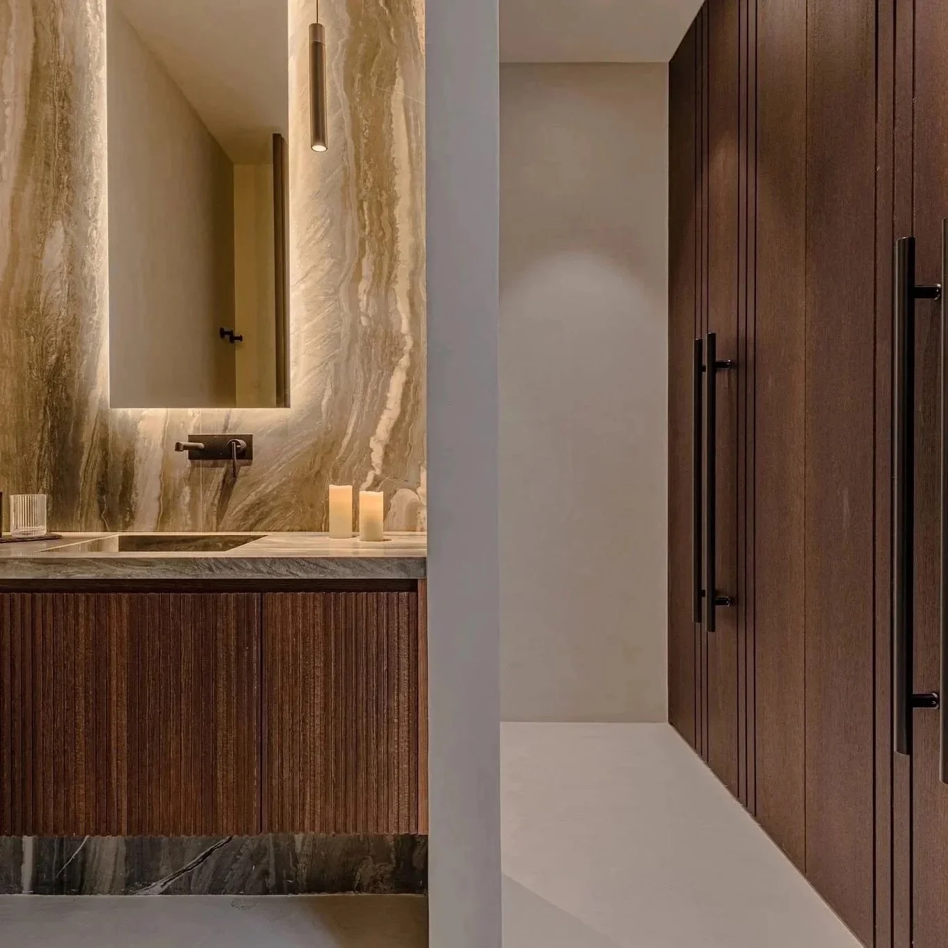 Baño moderno con lavabo de mármol, espejo con iluminación, velas y armario de madera