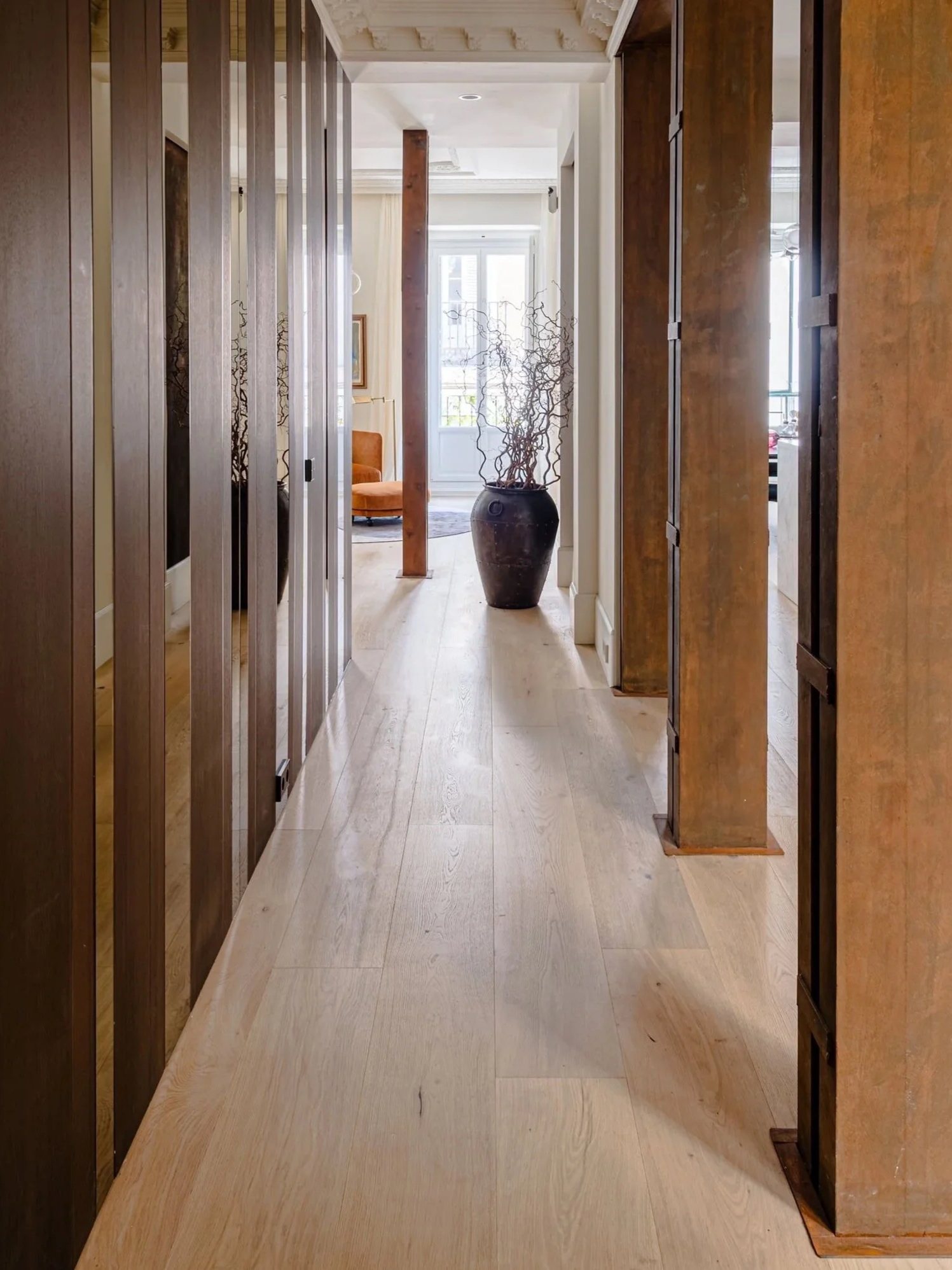 Pasillo de madera con planta decorativa en un jarrón grande en el fondo