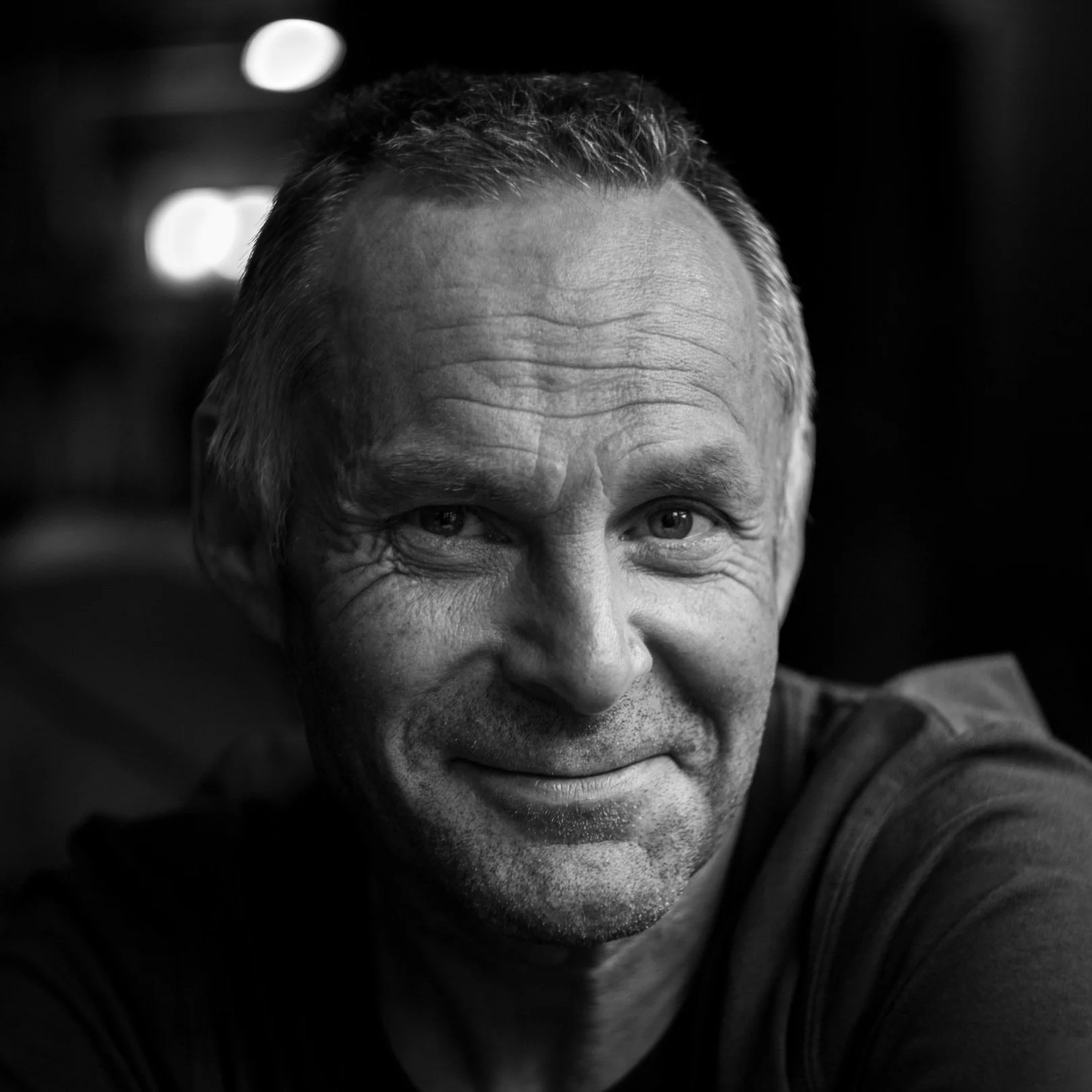Close-up black and white portrait of smiling middle-aged man with short hair.