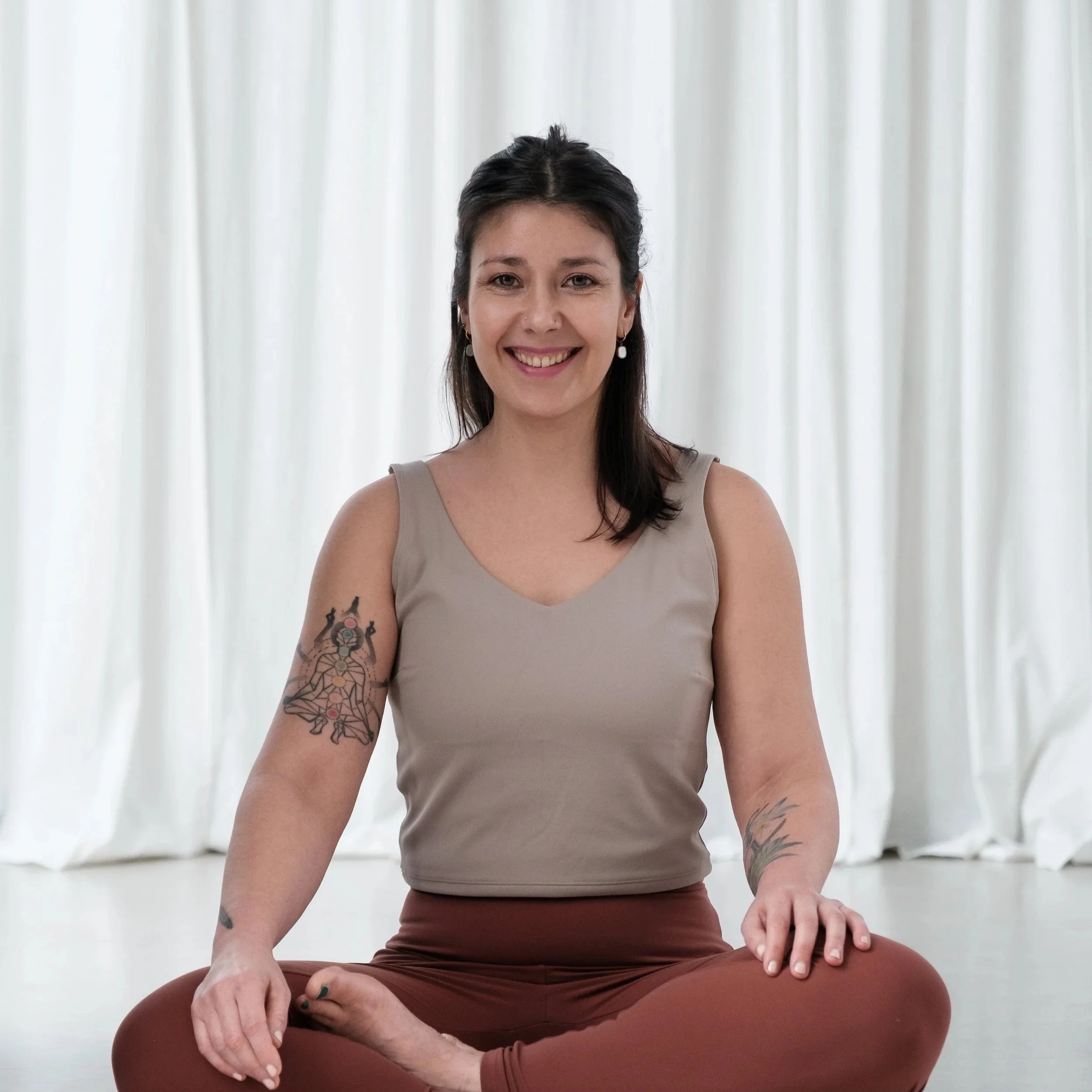 yoga teacher sitting in half lotus looking at camera