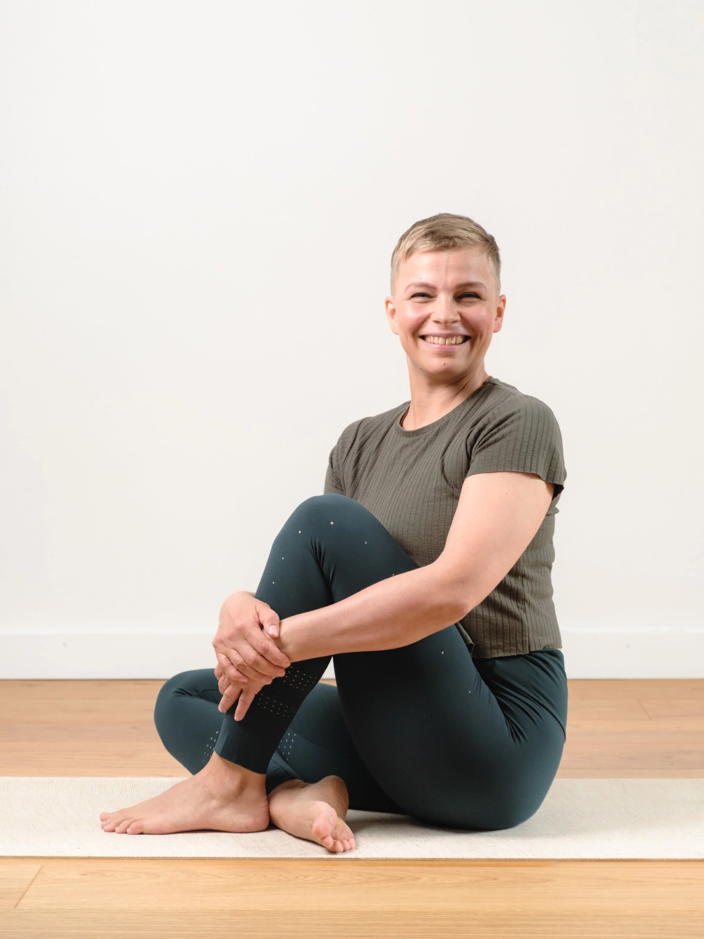 yoga teacher sitting in half lotus looking at camera