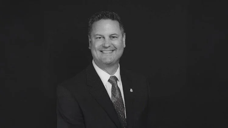 Black and white portrait of a smiling man in a suit and tie.