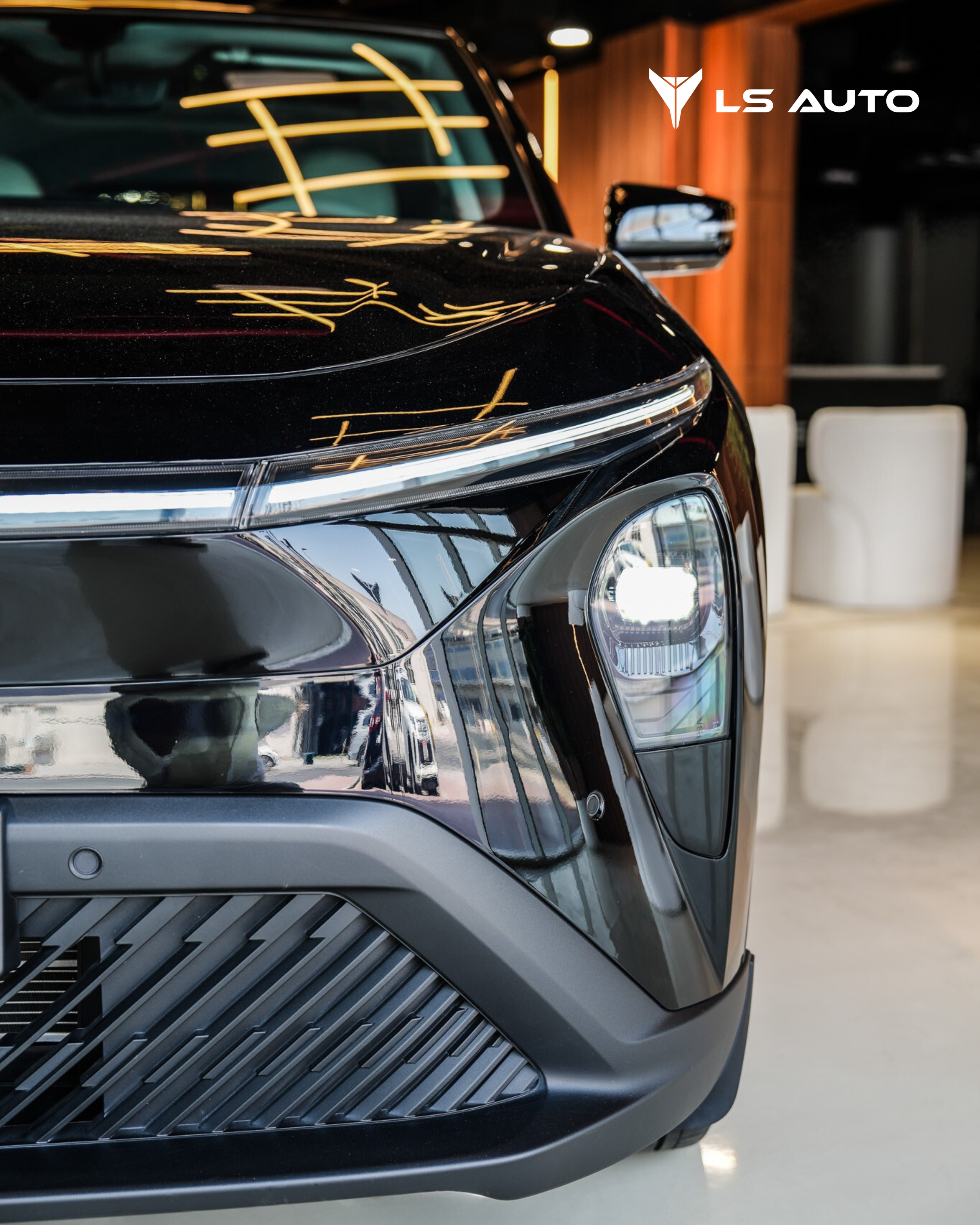 Close-up of the LEV01 electric vehicle in black, front end in the LS Auto UAE showroom, with reflections from overhead lighting and a logo reading 'LS Auto' in the top right corner.