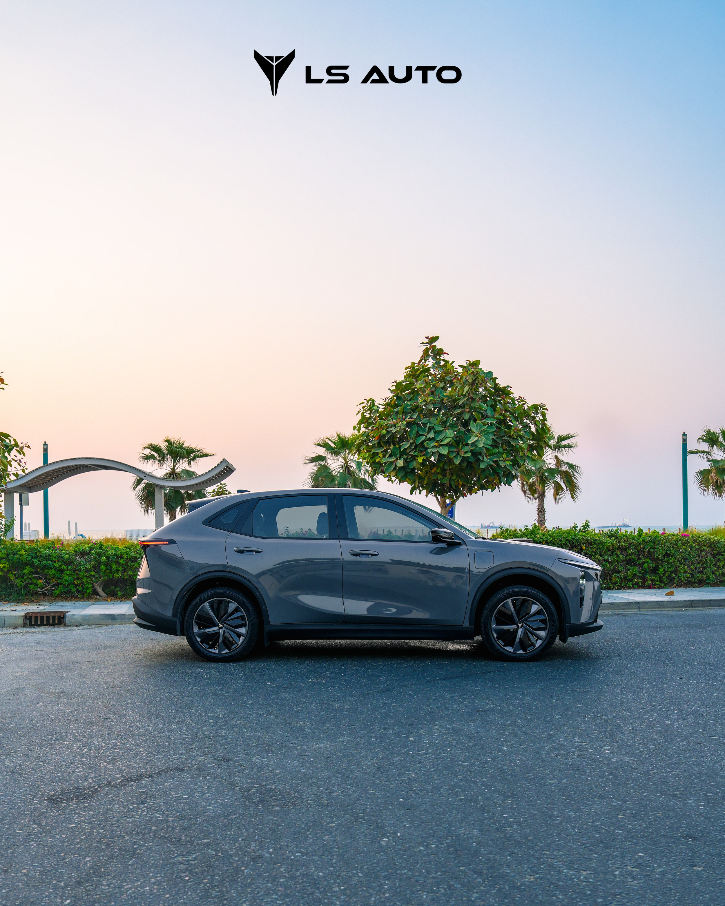 A sleek, dark gray LEV01 electric SUV parked on an empty street with palm trees and a landscaped area in the background, under a pastel-colored sky, with the 'LS Auto' logo at the top.