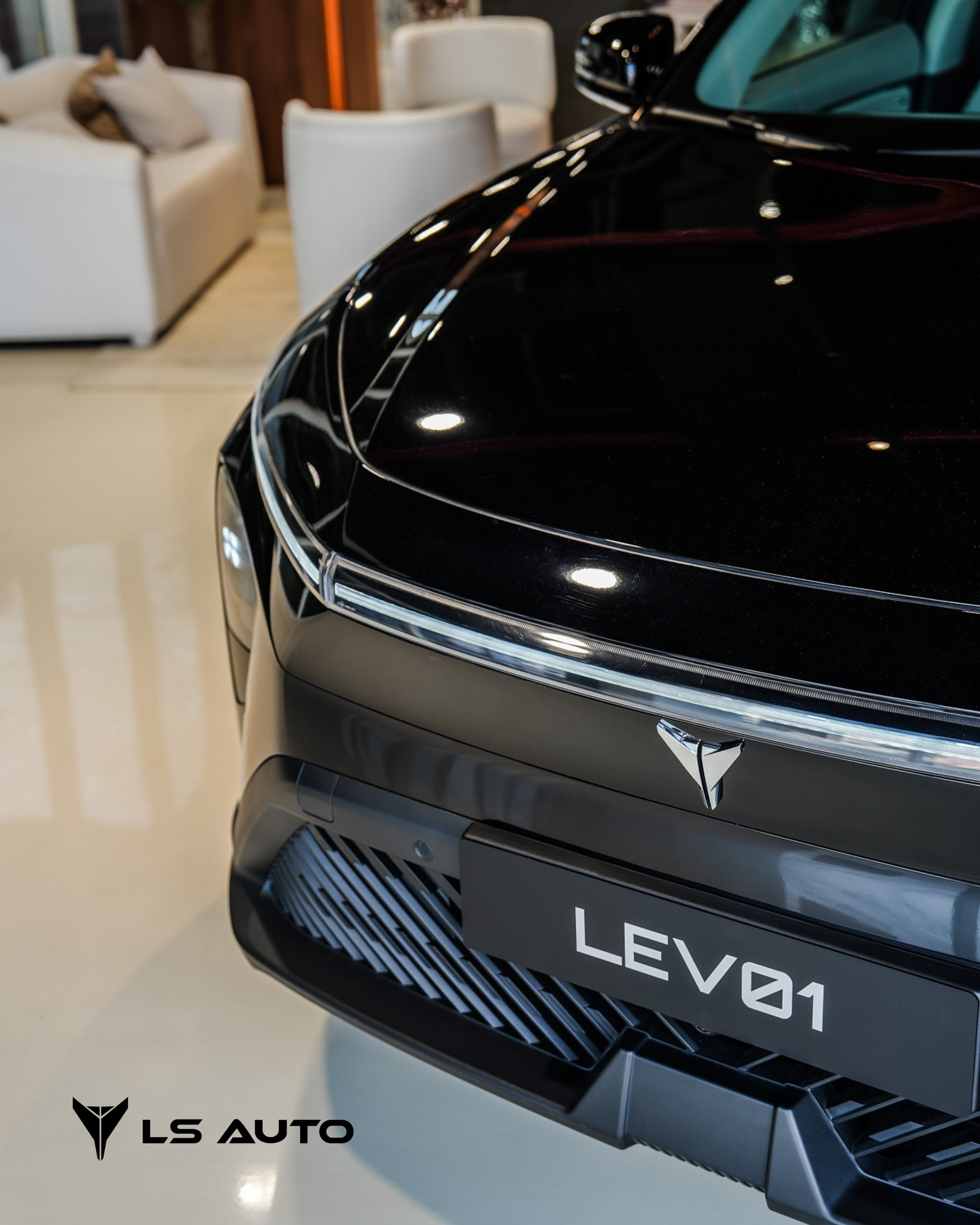 Close-up of a sleek black LEVO1 electric vehicle in a showroom, with LS Auto logo in the bottom left corner and a cozy seating area in the background.