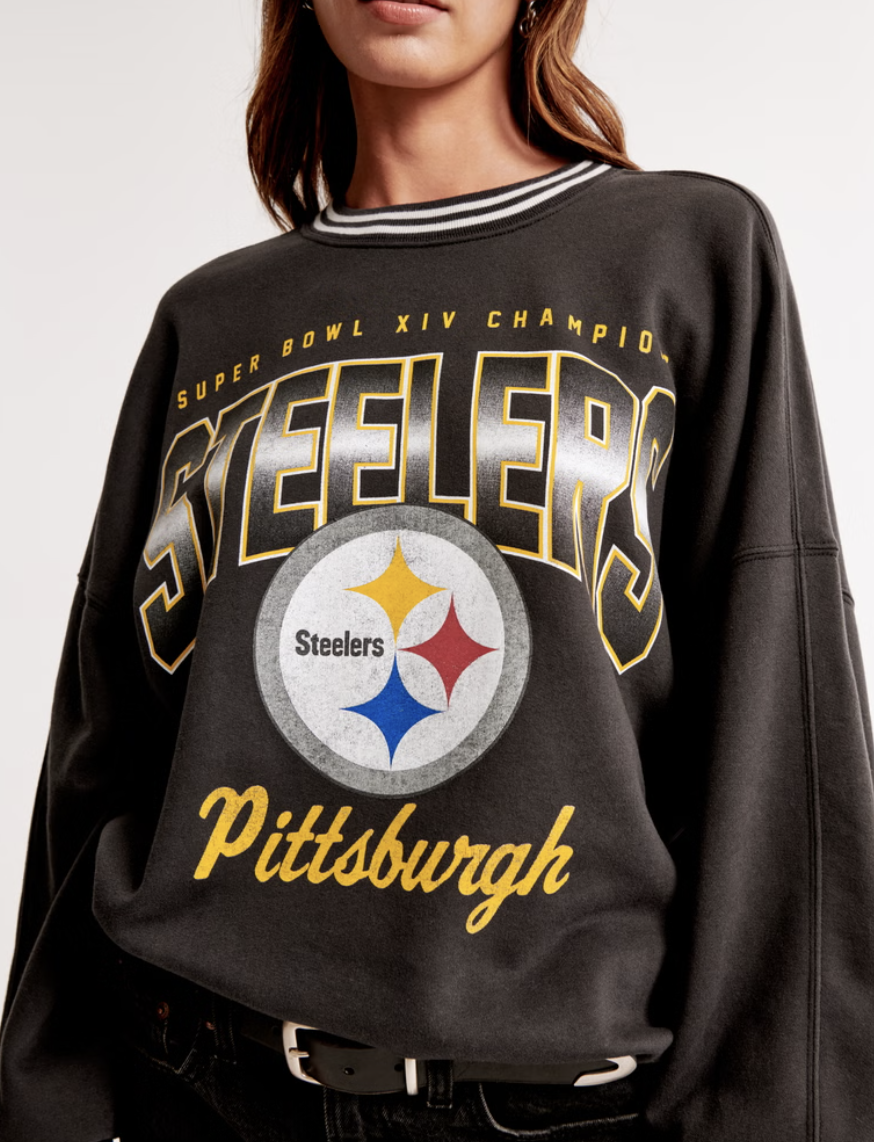 Woman wearing a Pittsburgh Steelers sweatshirt with text "Super Bowl XIV Champions" and the team logo.