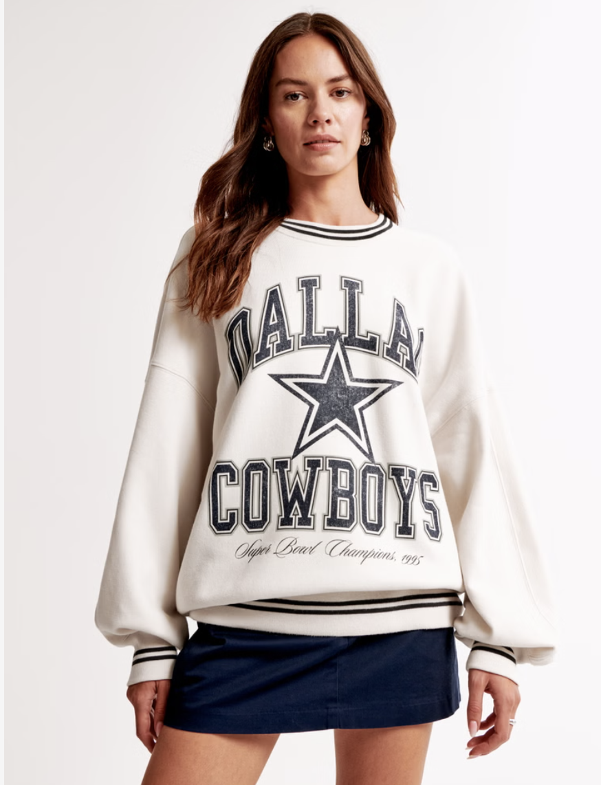 Woman wearing a white Dallas Cowboys sweatshirt and a dark skirt.