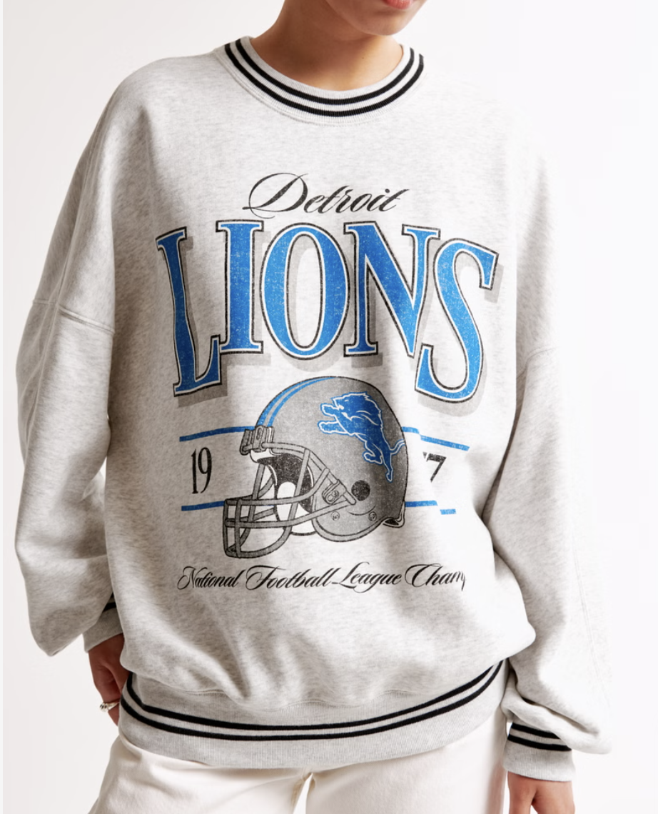 Person wearing a Detroit Lions sweatshirt with a football helmet graphic and text "Detroit Lions 1977 National Football League Champs."