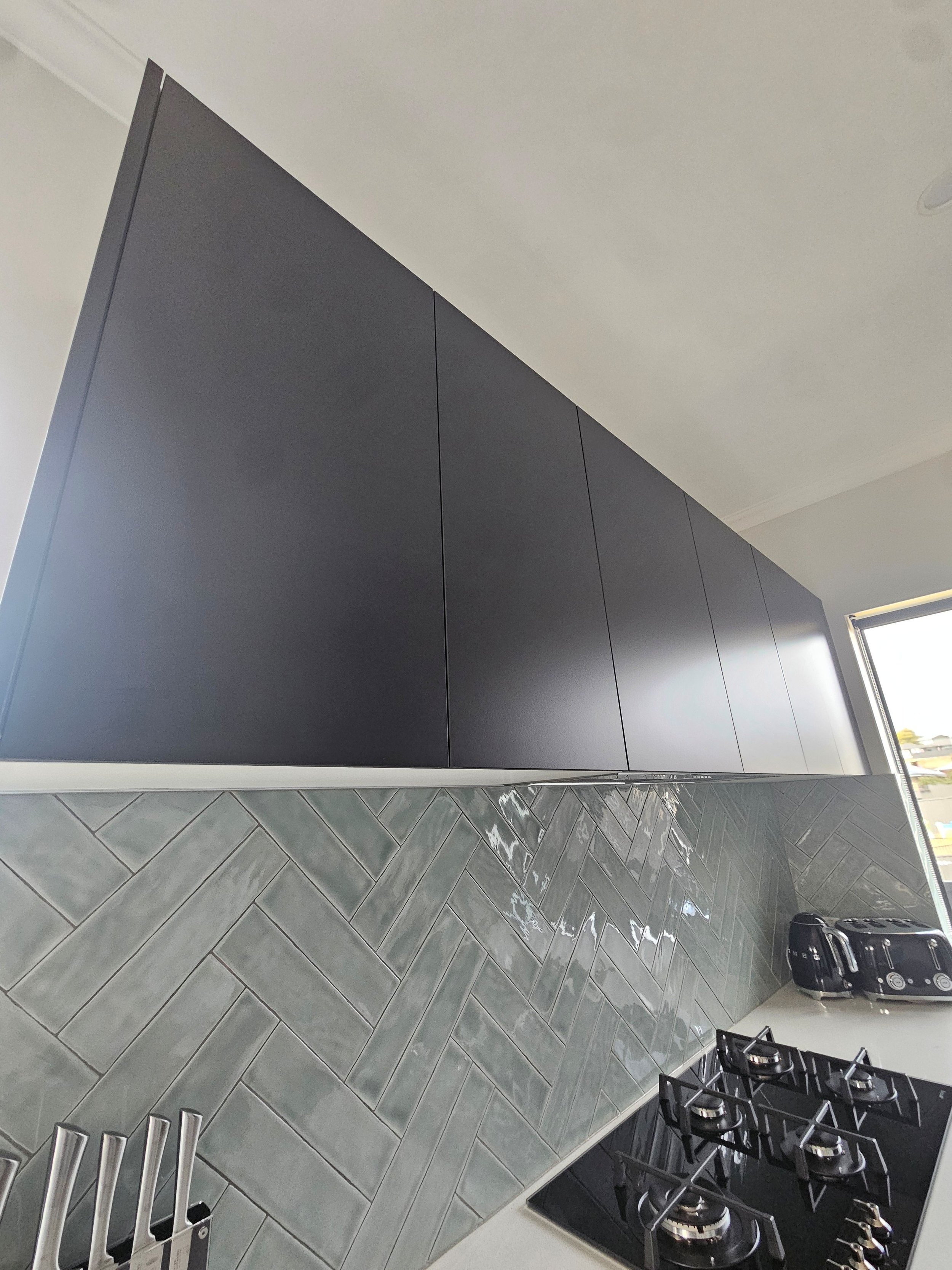 a modern clean kitchen with matte black cabinetry and smeg appliances