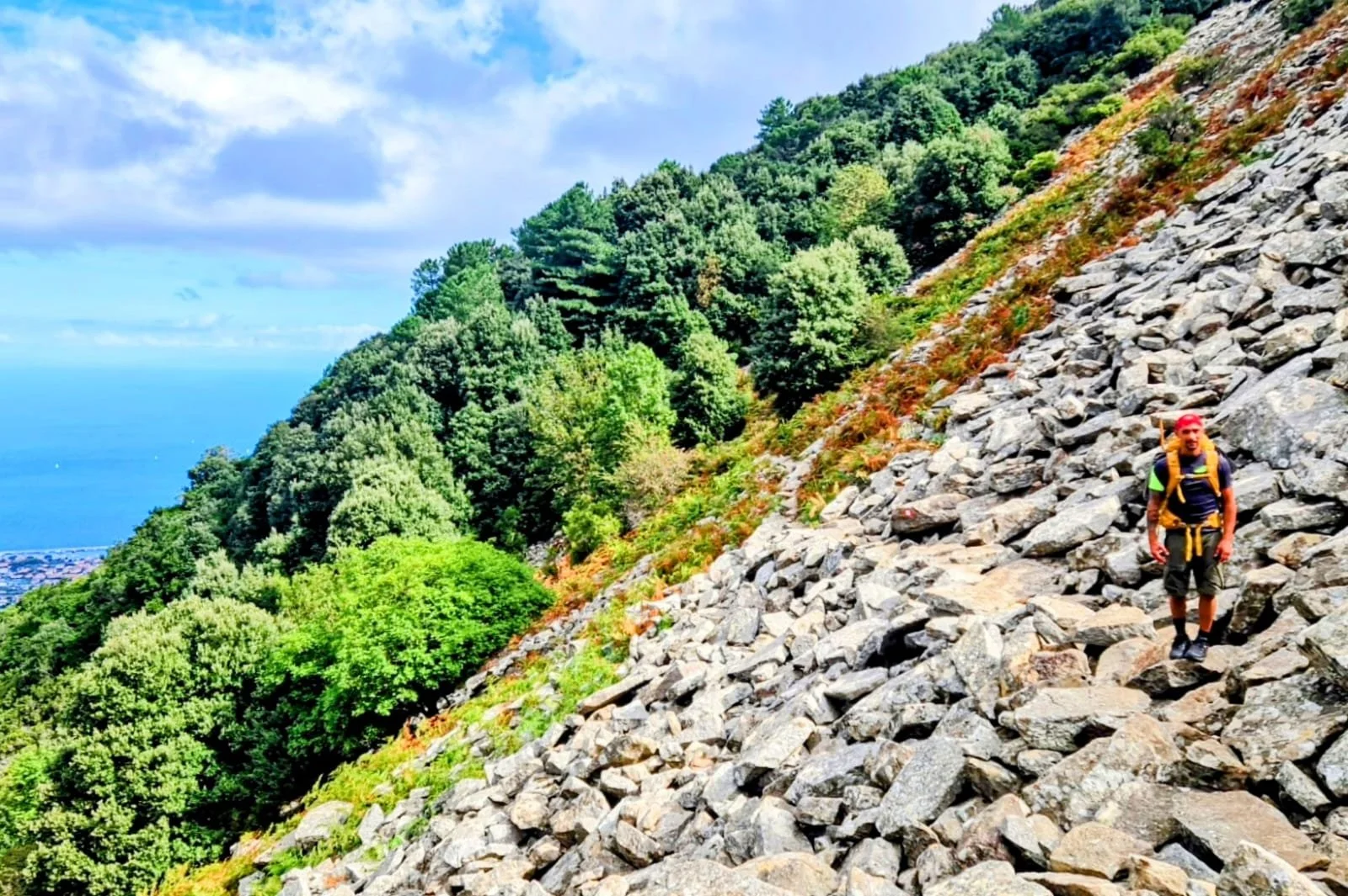 Escursionista che cammina su rocce con vista sul mare lungo la Grande Traversata Elbana