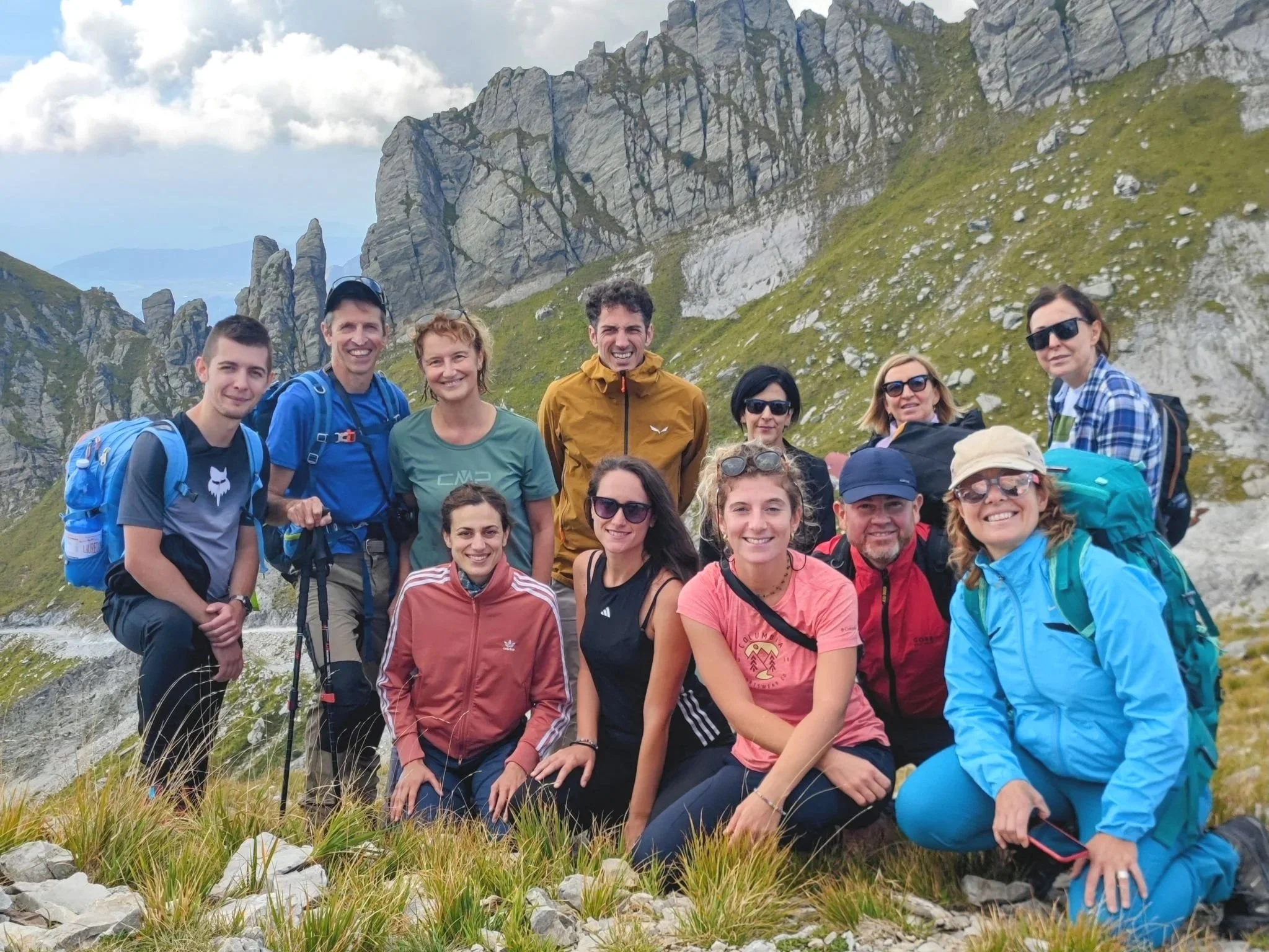 Gruppo di escursionisti sorridenti durante un trekking nelle Alpi Apuane, con le montagne sullo sfondo