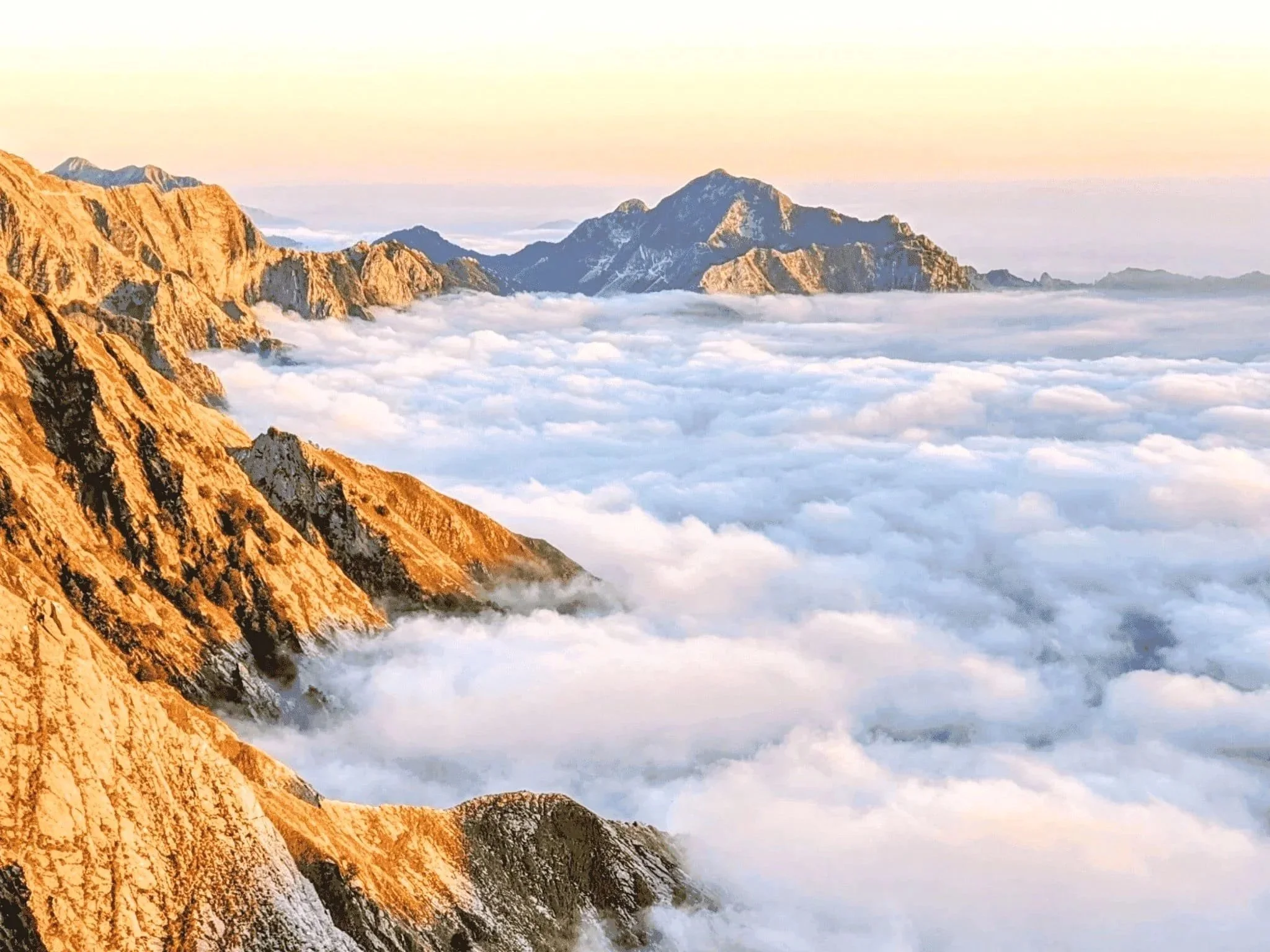 Tramonto sulle Alpi Apuane con le montagne illuminate dalla luce dorata durante un trekking