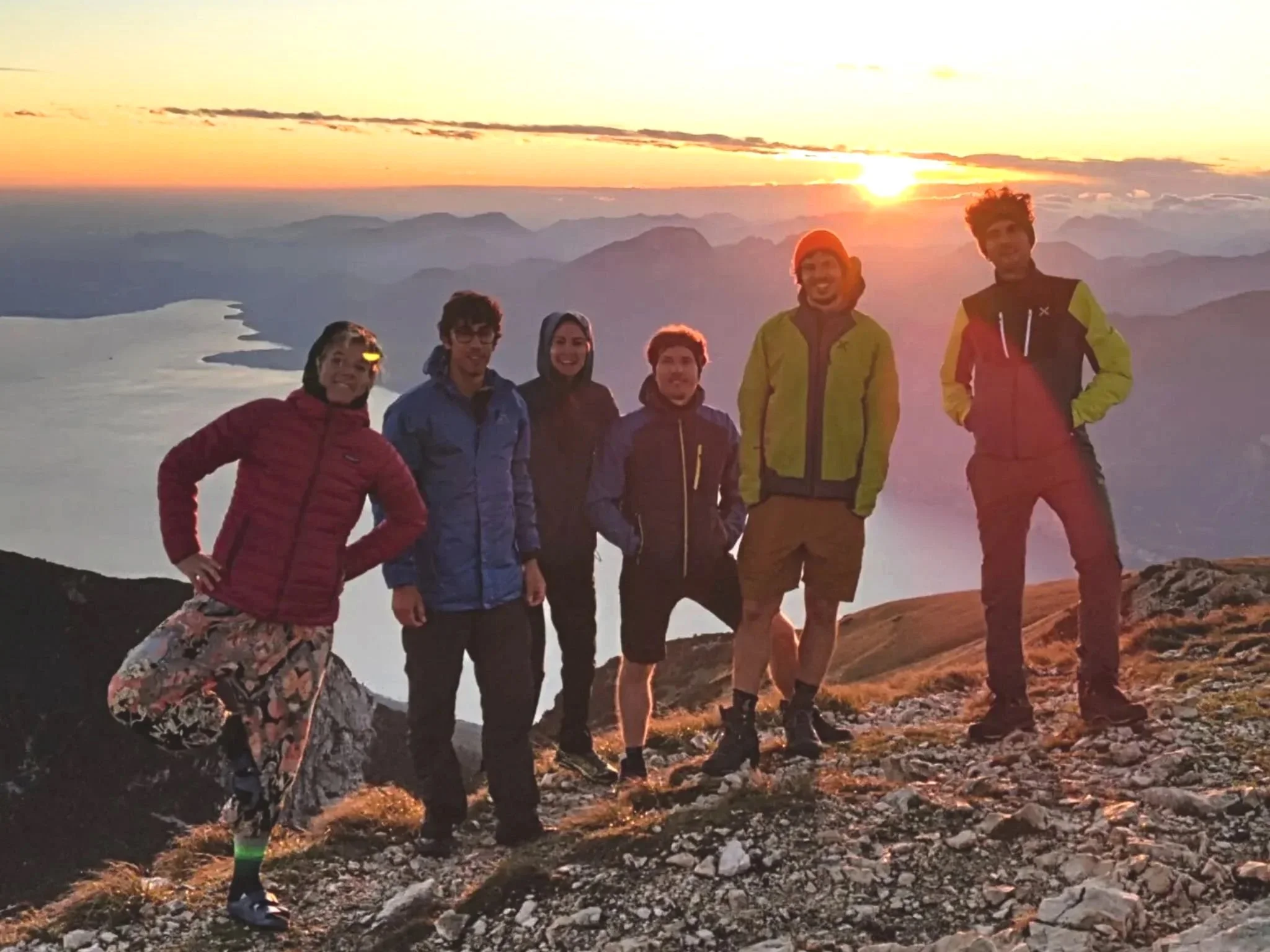 Gruppo di escursionisti sul Monte Baldo con il Lago di Garda e il tramonto sullo sfondo
