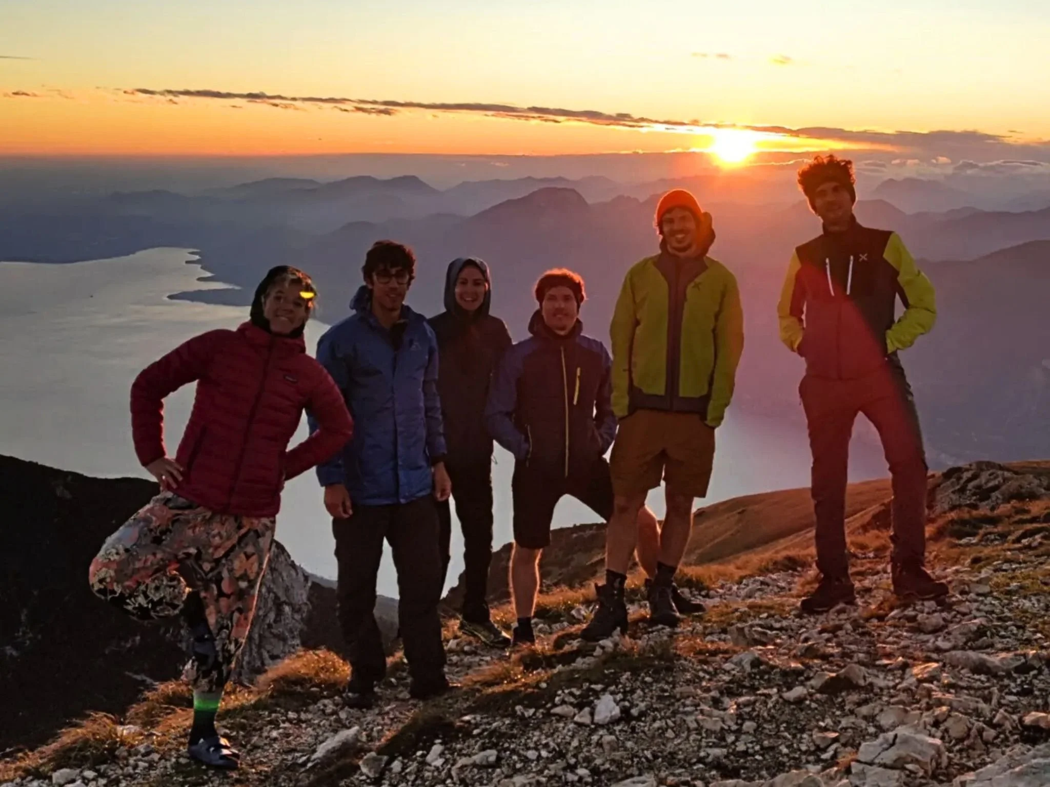 Gruppo di escursionisti sul Monte Baldo con il Lago di Garda e il tramonto sullo sfondo