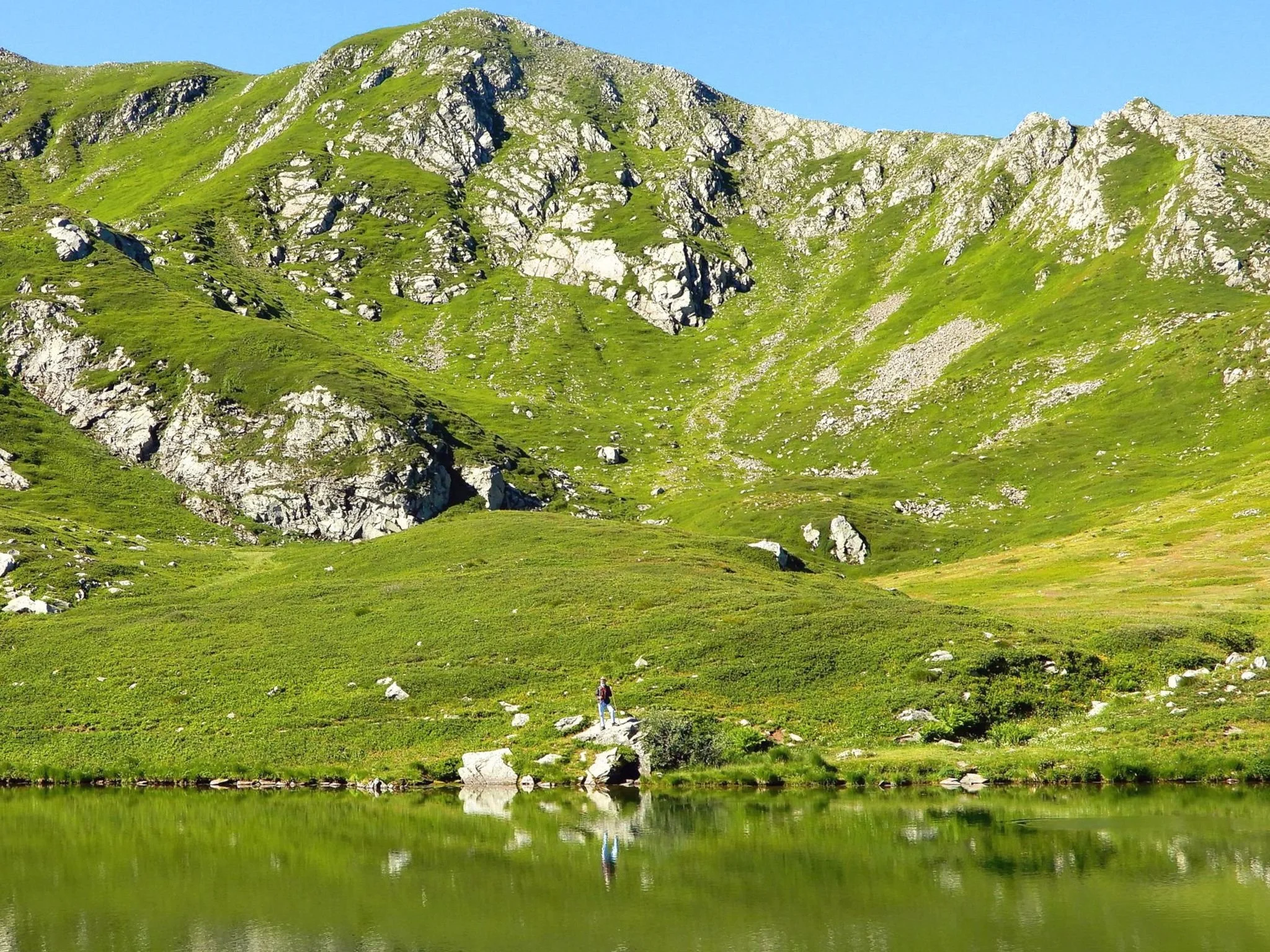 Escursionista in cammino sul Monte Cusna con vista sul Lago Bargetana e le creste dell’Appennino tosco-emiliano