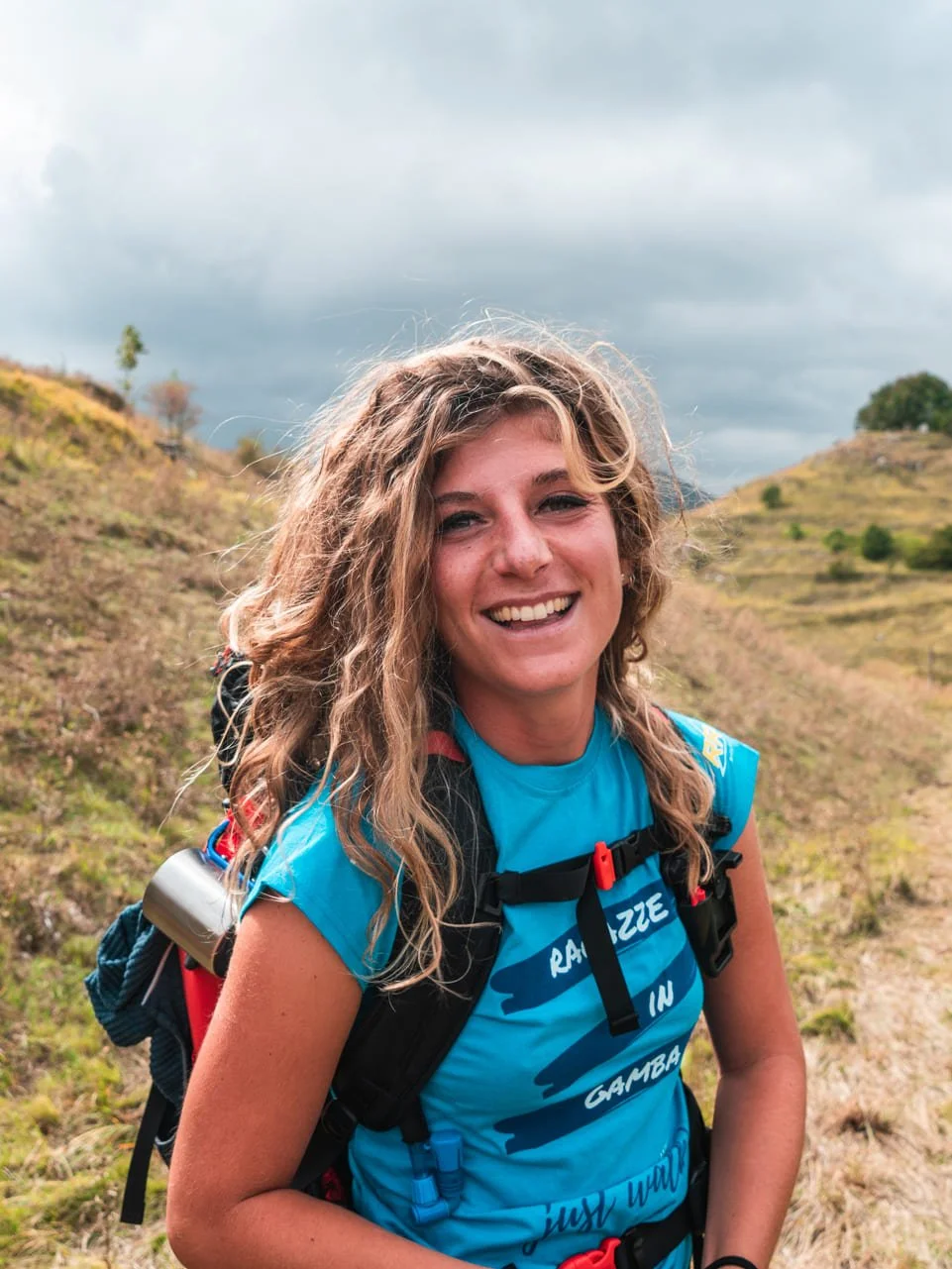 Ragazza sorridente con lo zaino in spalla durante un trekking a piedi