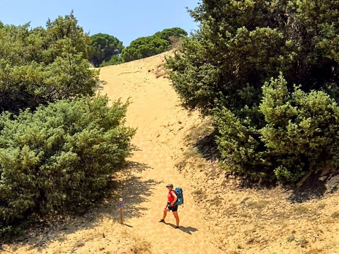 Escursionista in cammino su una duna sabbiosa lungo il Cammino Minerario di Santa Barbara in Sardegna