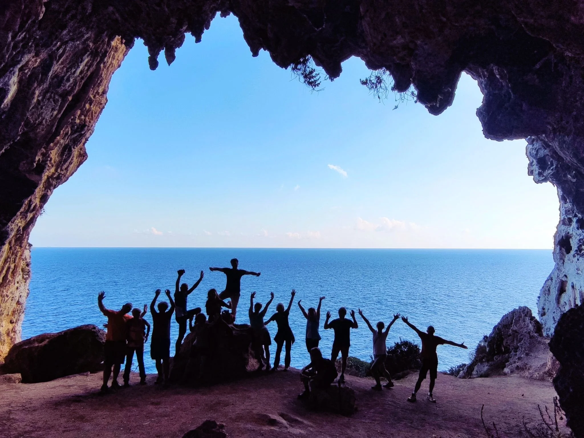Gruppo di camminatori sul Cammino del Salento in una grotta con vista mare