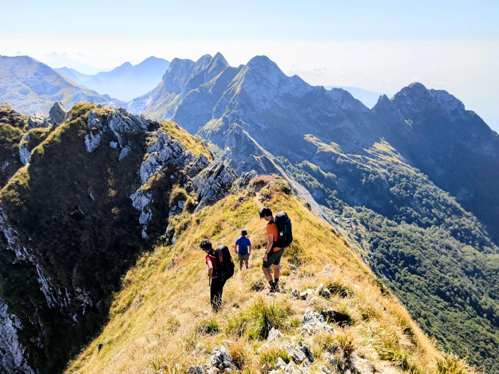 Escursionisti che camminano durante un trekking nelle Alpi Apuane, con le montagne sullo sfondo
