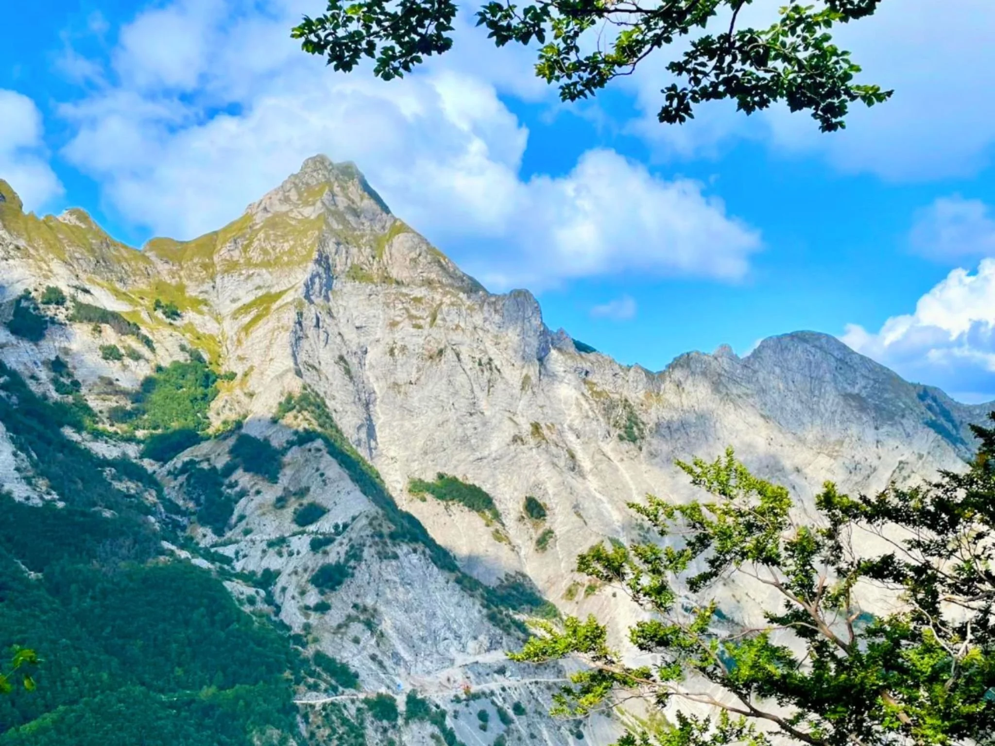 Veduta di una montagna delle Alpi Apuane con cielo azzurro e nuvole sullo sfondo durante un trekking