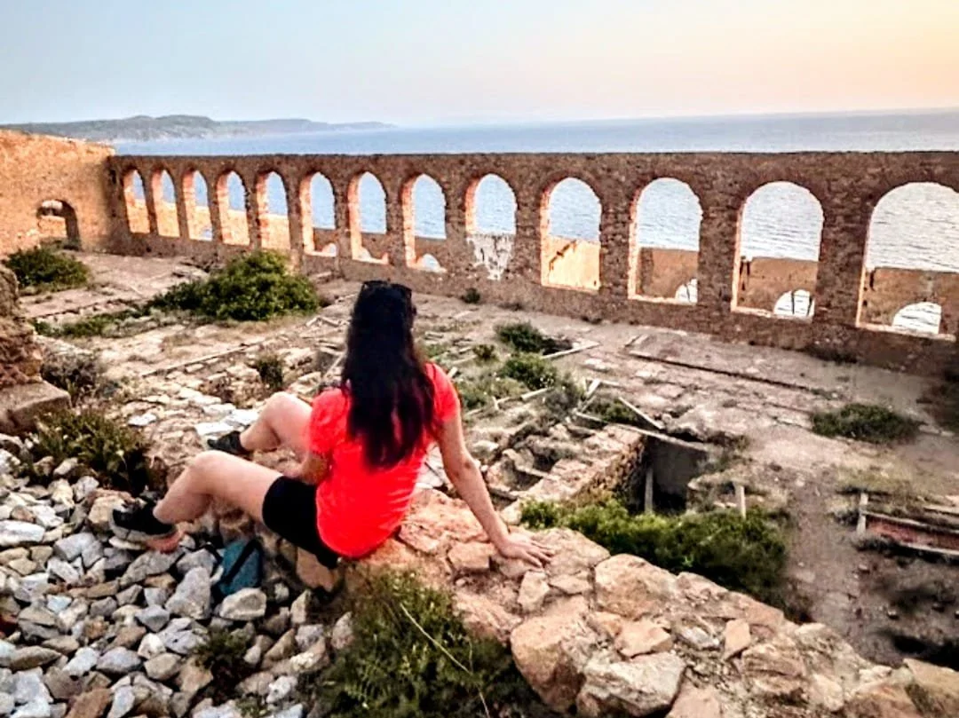 Ragazza che osserva l’orizzonte al tramonto davanti alla Laveria Lamarmora sul Cammino Minerario di Santa Barbara in Sardegna