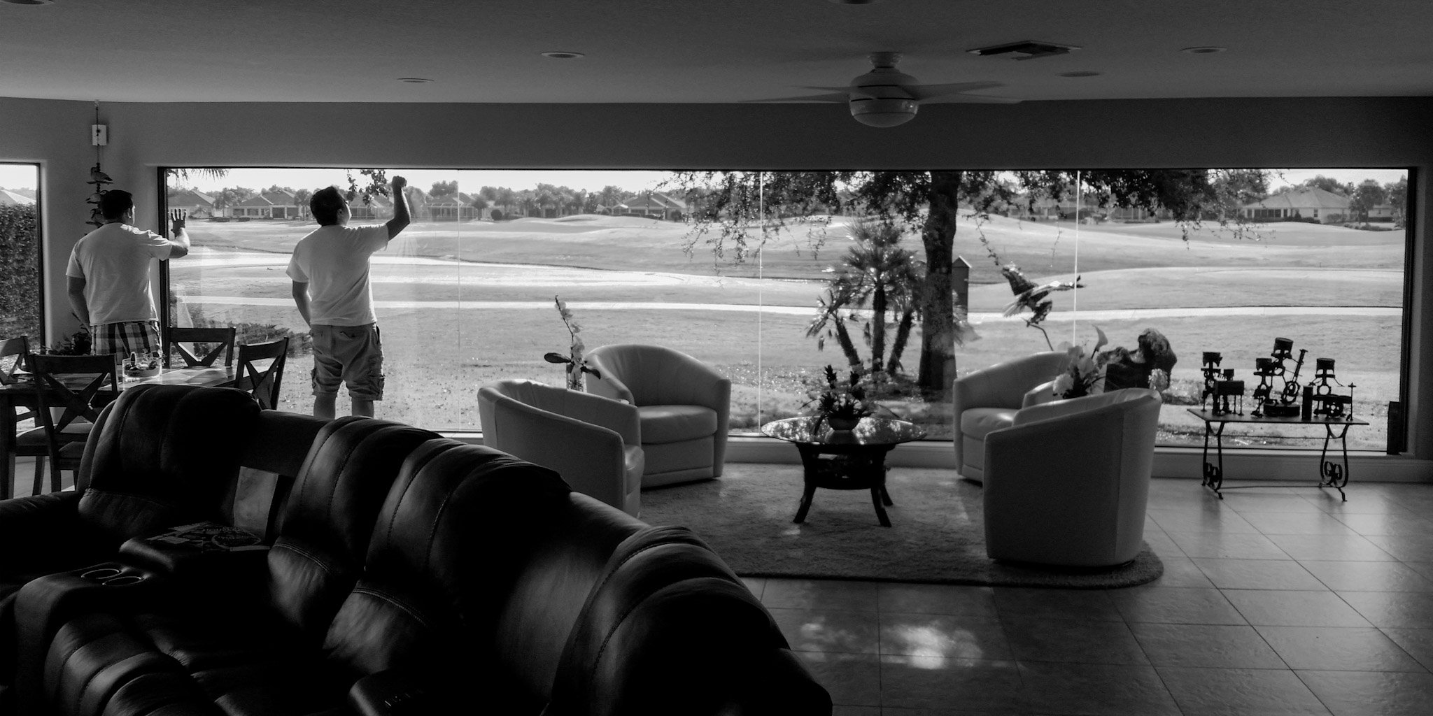 Stanton Barbas and Skyeler Schmidt performing an initial inspection of a large glass wall overlooking a golf course at a Lely Resort home in Naples
